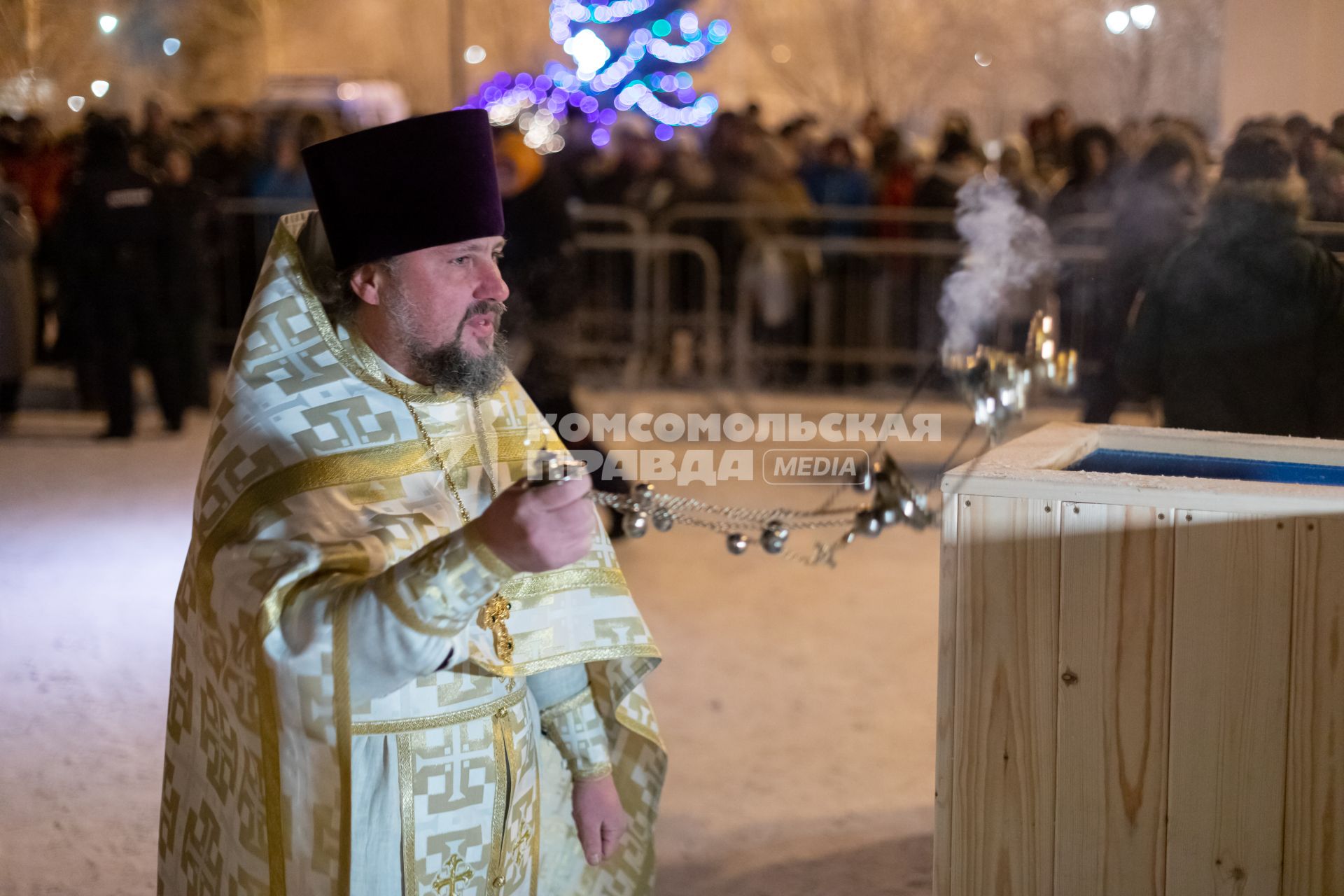 Красноярск. Священнослужитель освящает воду в иордани во время празднования Крещения .