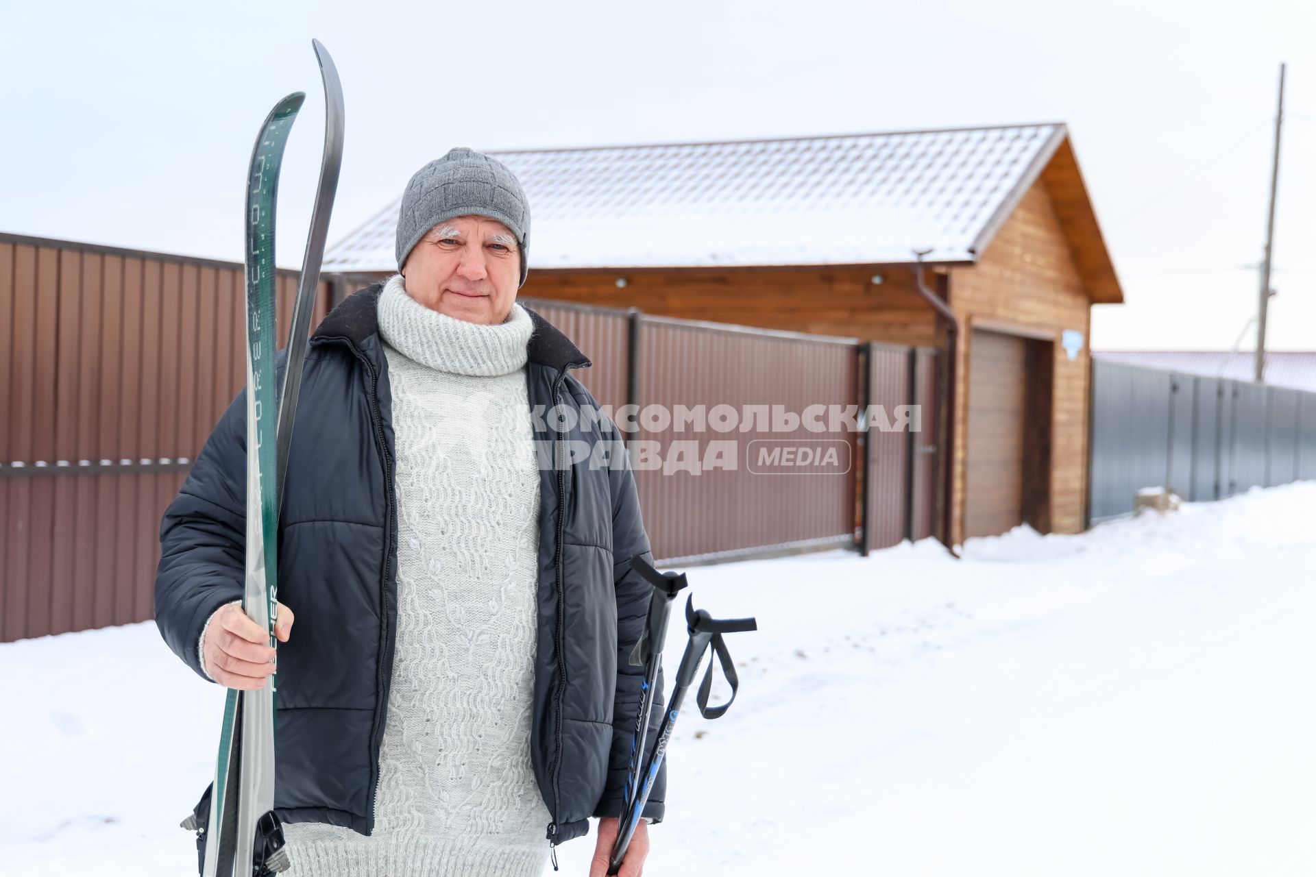 Красноярск. Пожилой мужчина с лыжами у загородного дома.