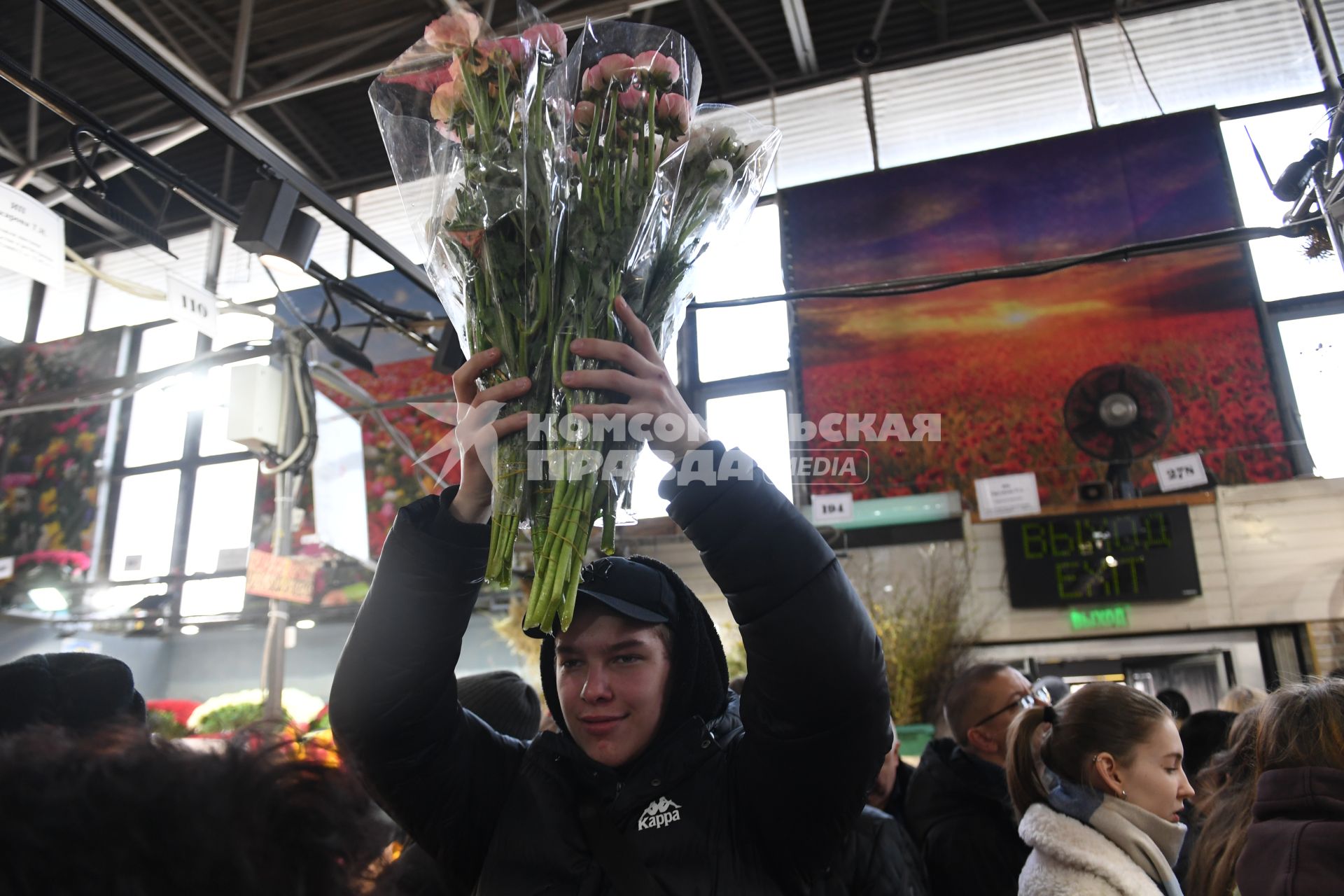 Москва. Молодой человек с букетами цветов на Рижском цветочном рынке в преддверии праздника 8 Марта.