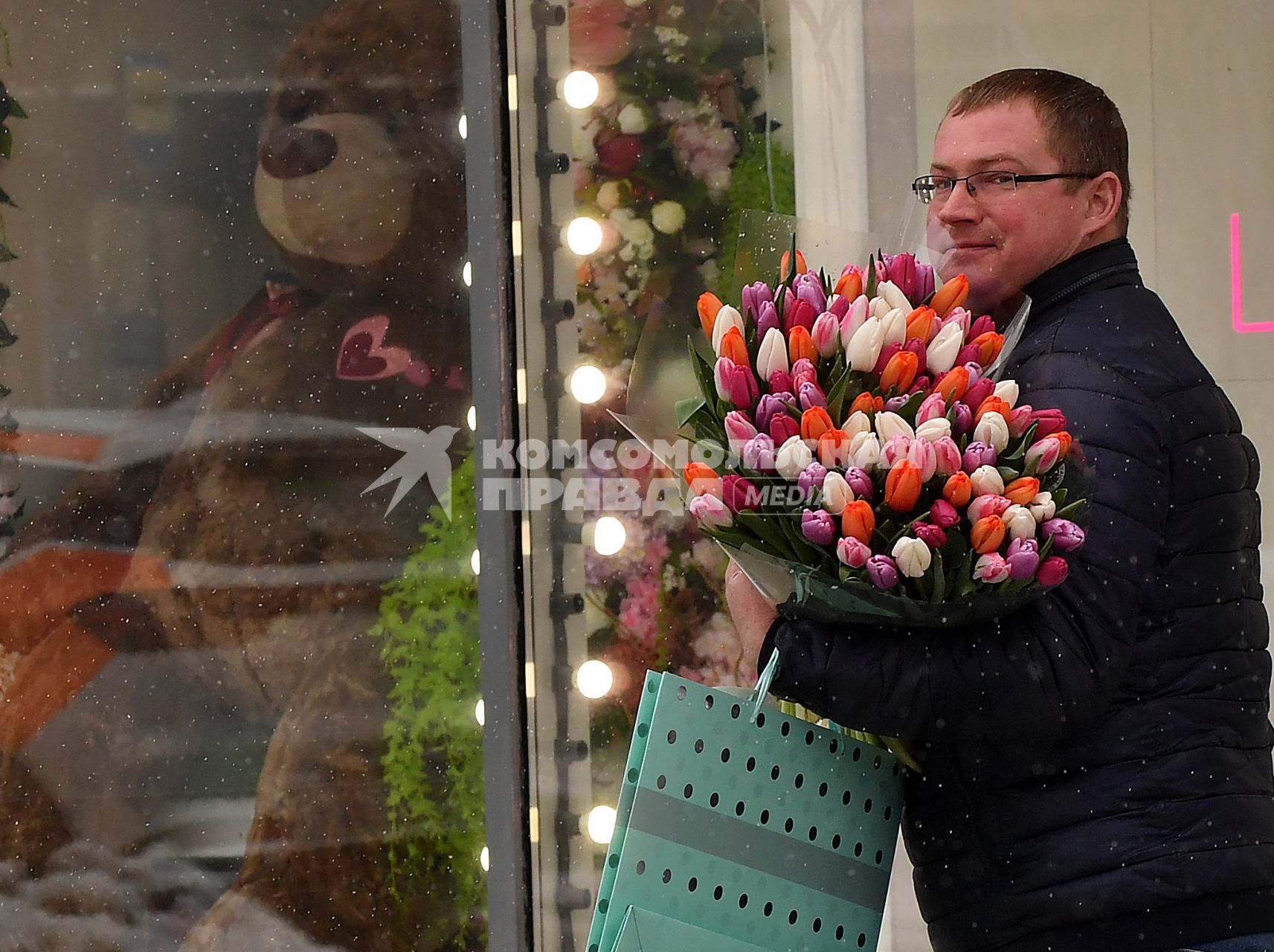 Москва. Мужчина с букетом  цветов у  витрины магазина  в международный женский день 8 Марта.