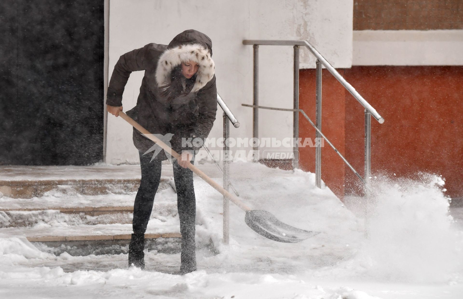 Москва.  Женщина расчищает снег на улице.