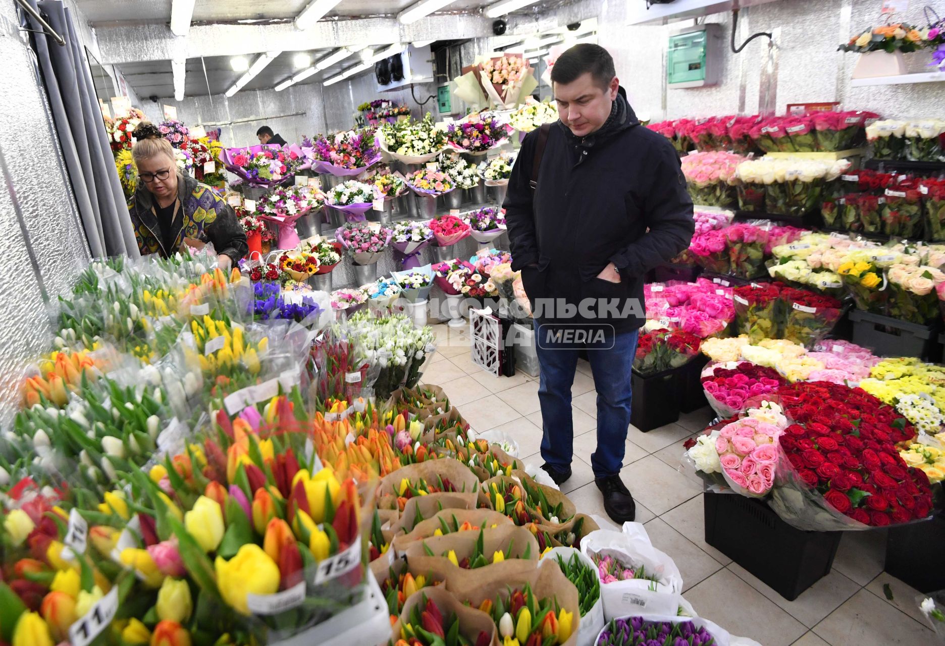 Москва.   Мужчина покупает цветы на рынке в международный женский день 8 Марта