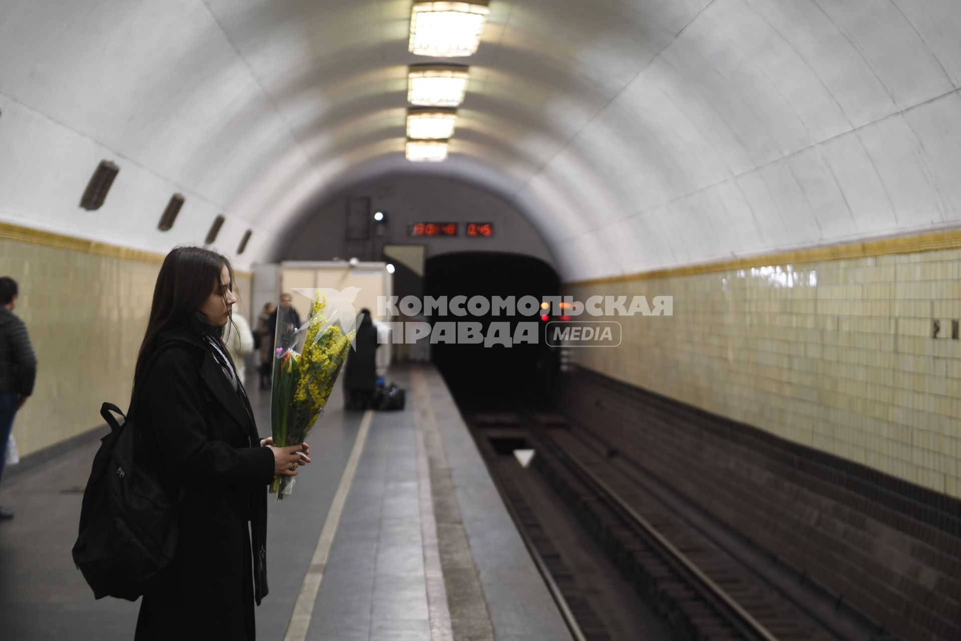 Москва. Девушка с мимозой в руках на станции метро `Рижская`.