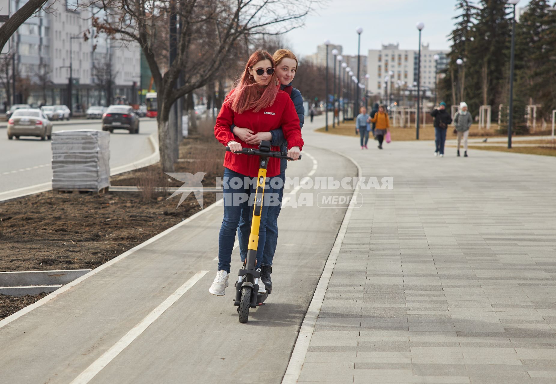 Пермь. Девушки едут на электросамокате по выделенной полосе для самокатов и велосипедов.