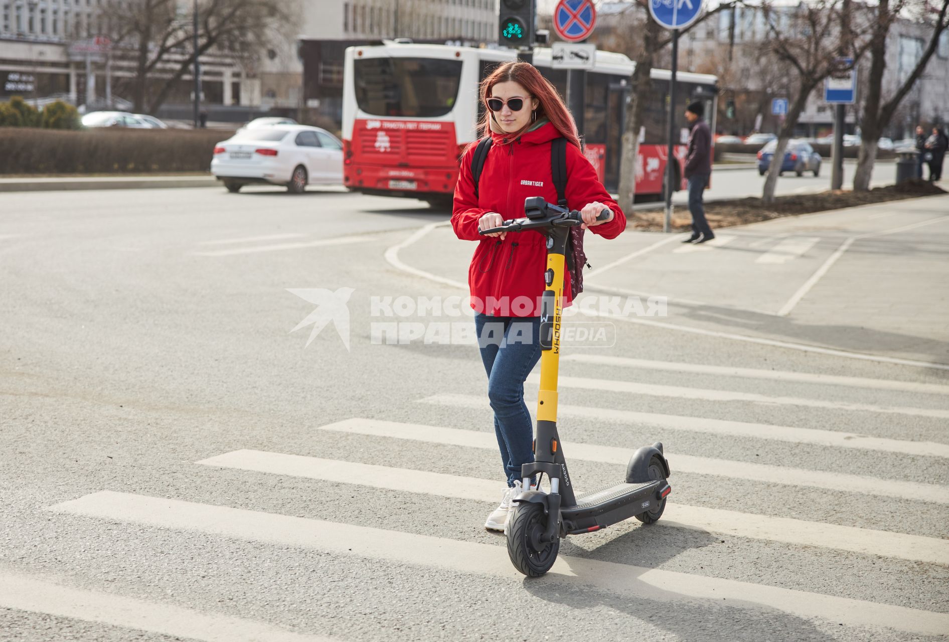 Пермь. Девушка ведет электросамокат рядом с собой и переходит дорогу пешком.