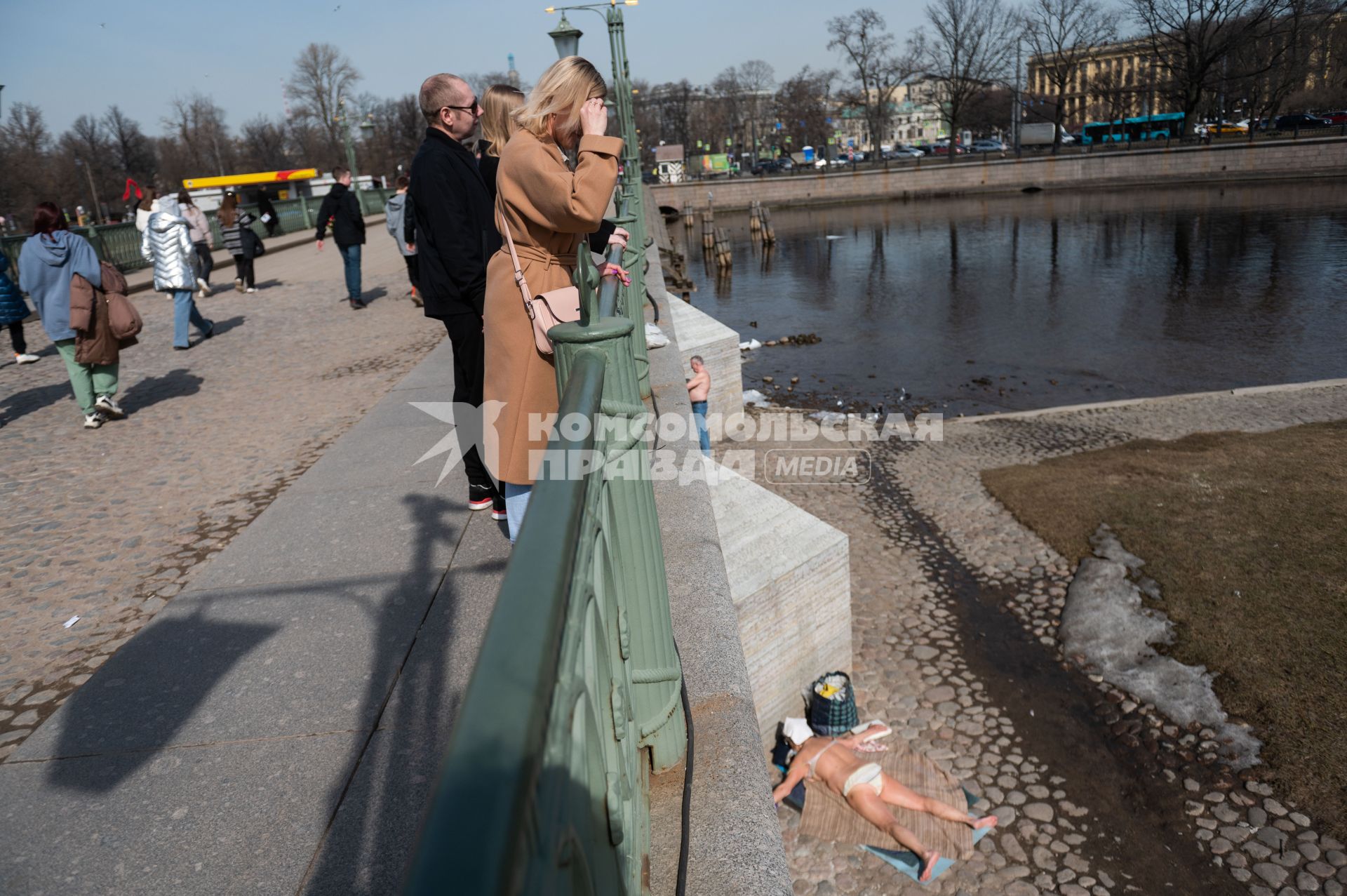 Санкт-Петербург. Женщина на мосту смотрит на загорающих людей у Петропавловской крепости.