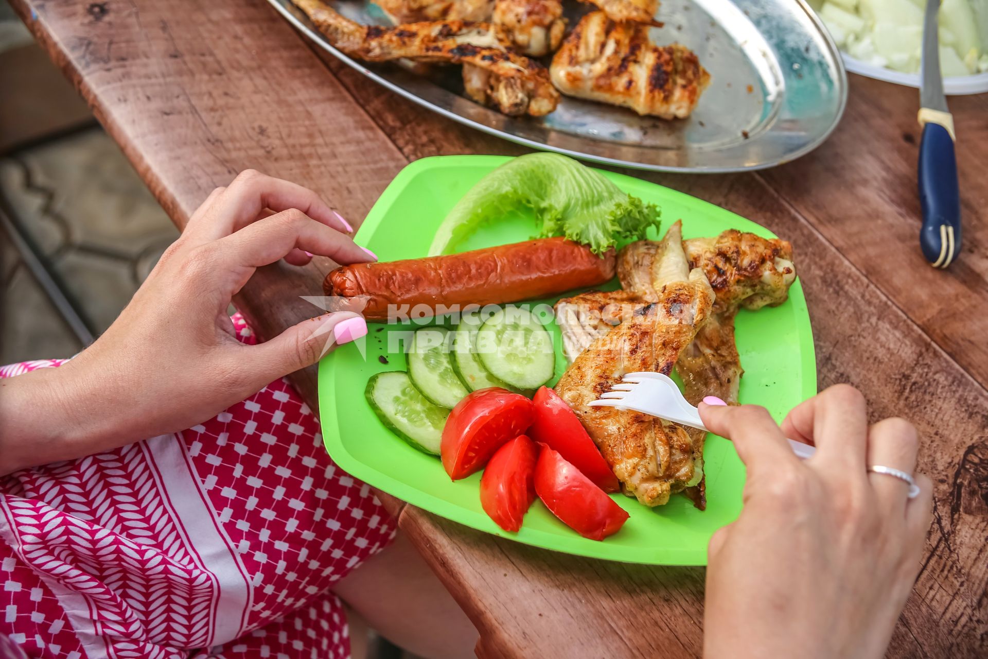 Красноярск. Жареные куриные крылья, сосиска и овощи на тарелке.