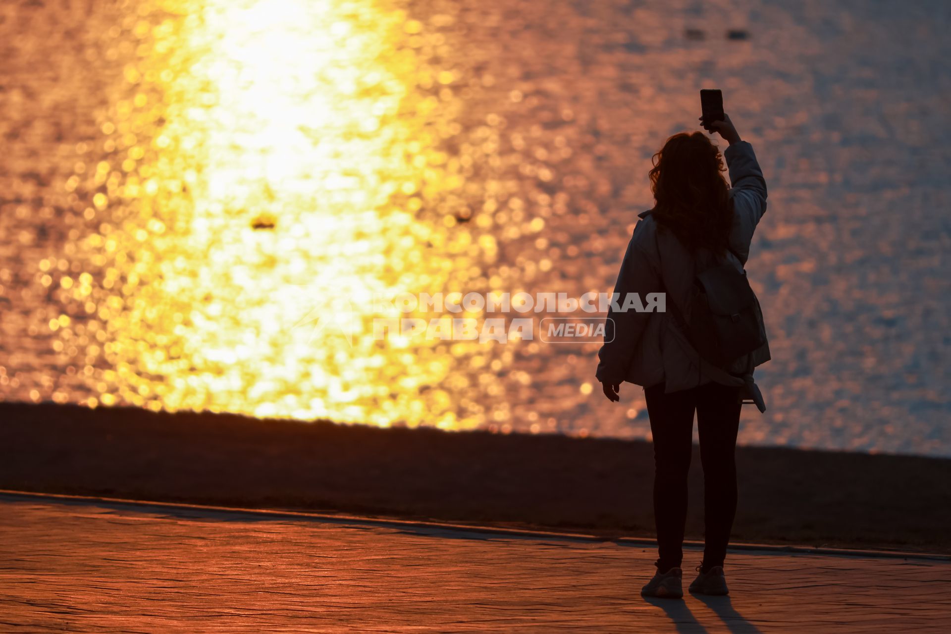 Красноярск. Девушка делает селфи на набережной во время заката.