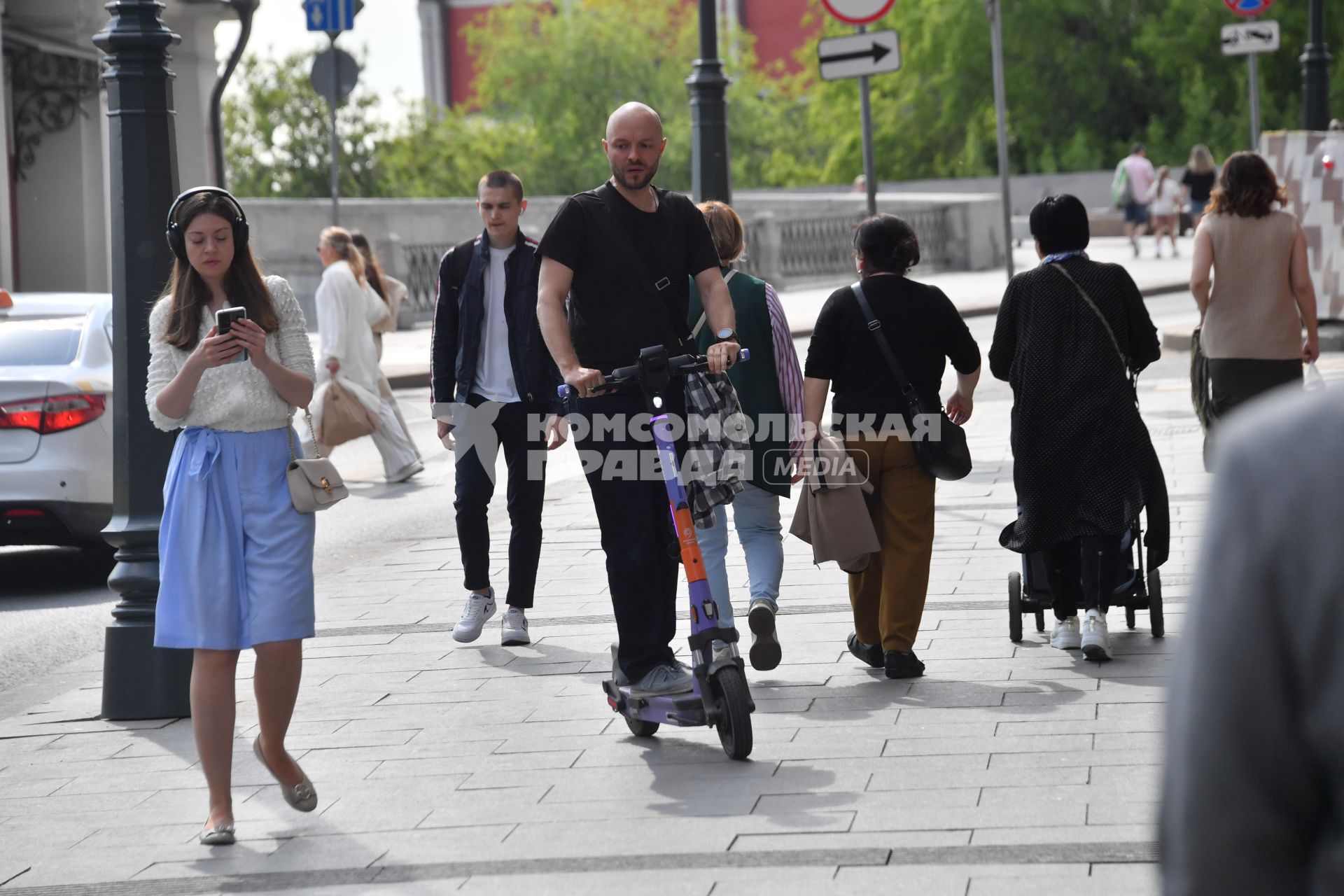 Москва. Мужчина едет на электросамокате по тротуару.