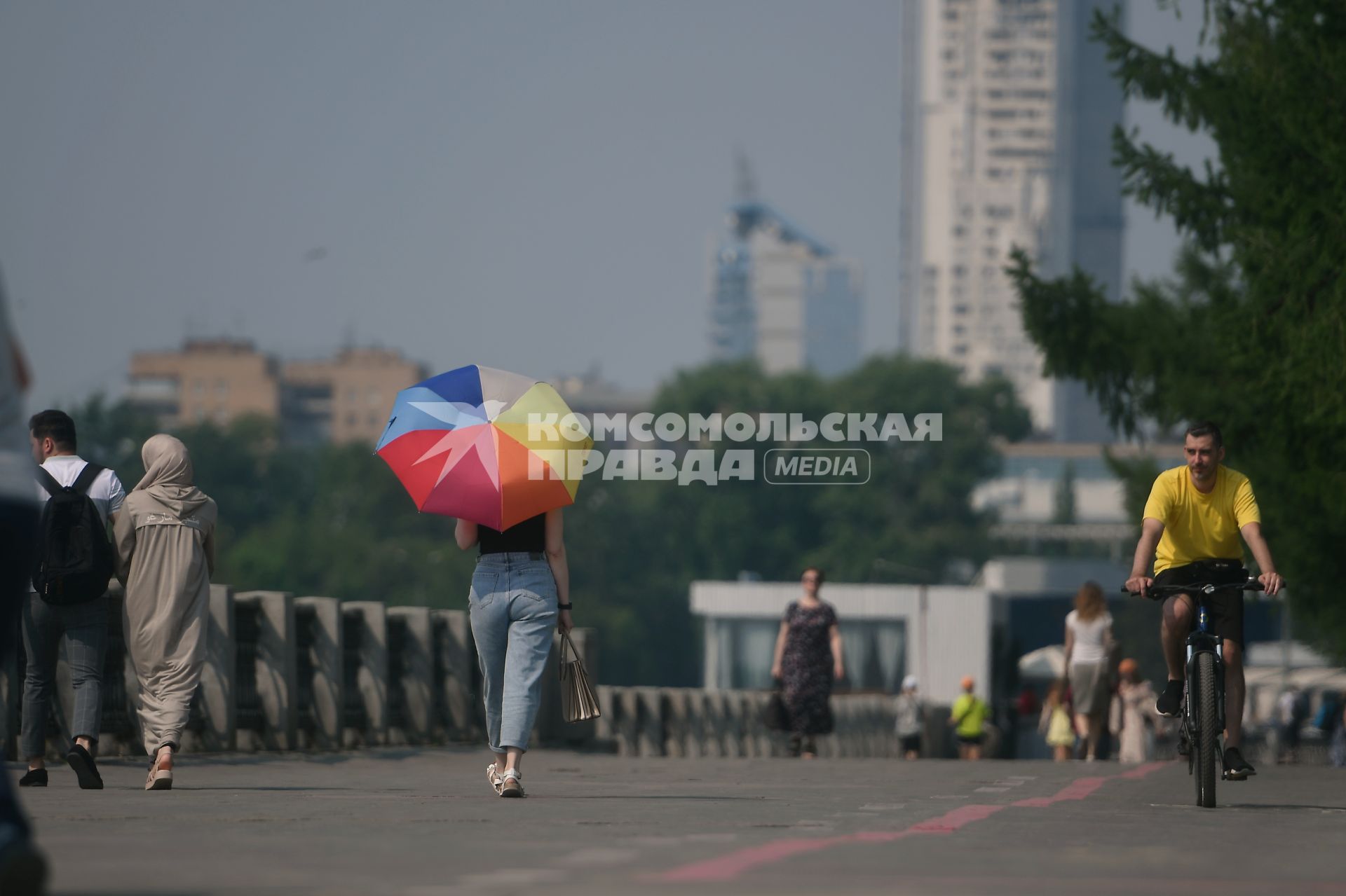 Екатеринбург. Девушка с разноцветным зонтом идет по плотинке, во время жары