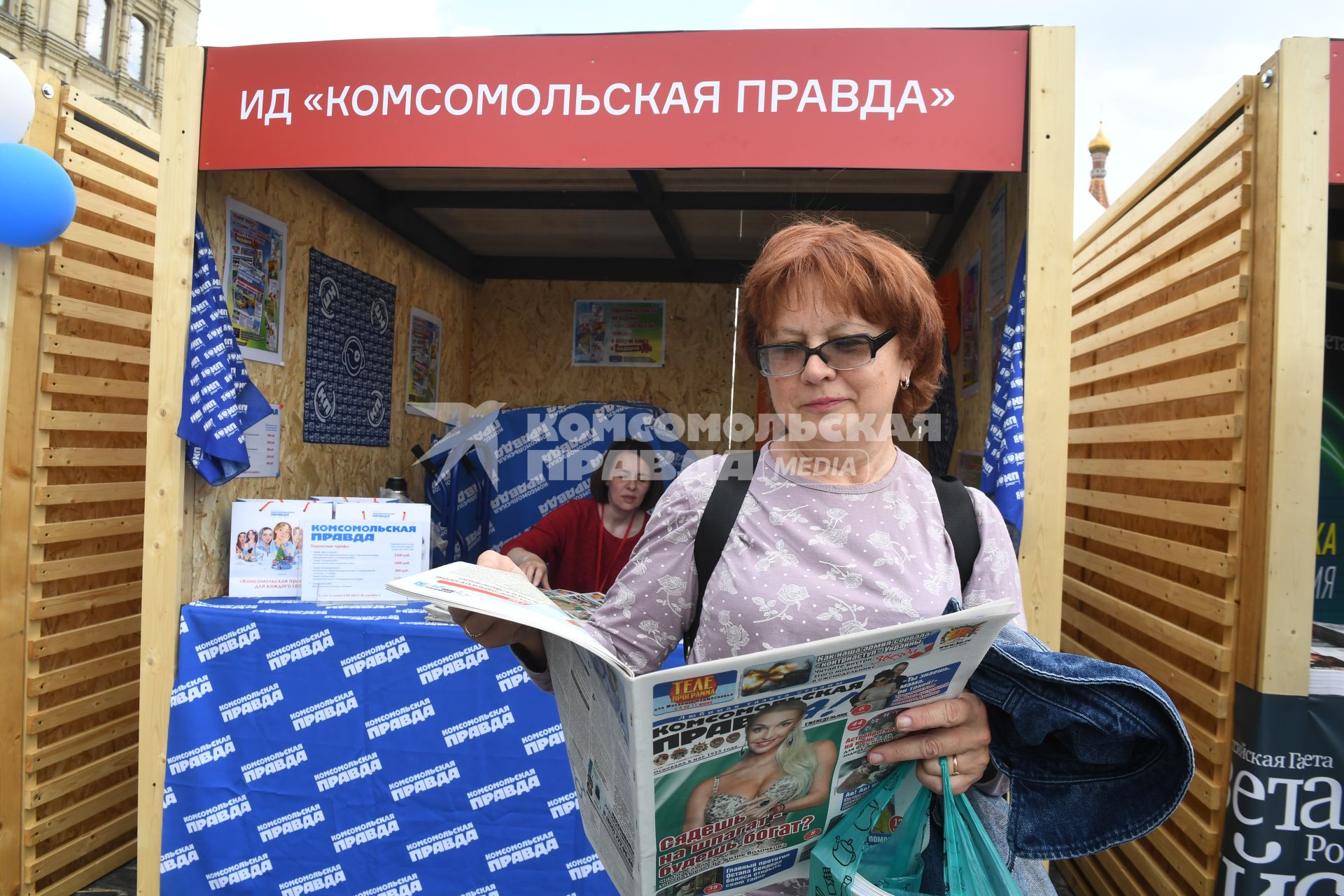 Москва. Женщина читает газету у стенда Издательского дома `Комсомольская правда` на IX ежегодном книжном фестивале `Красная площадь`.