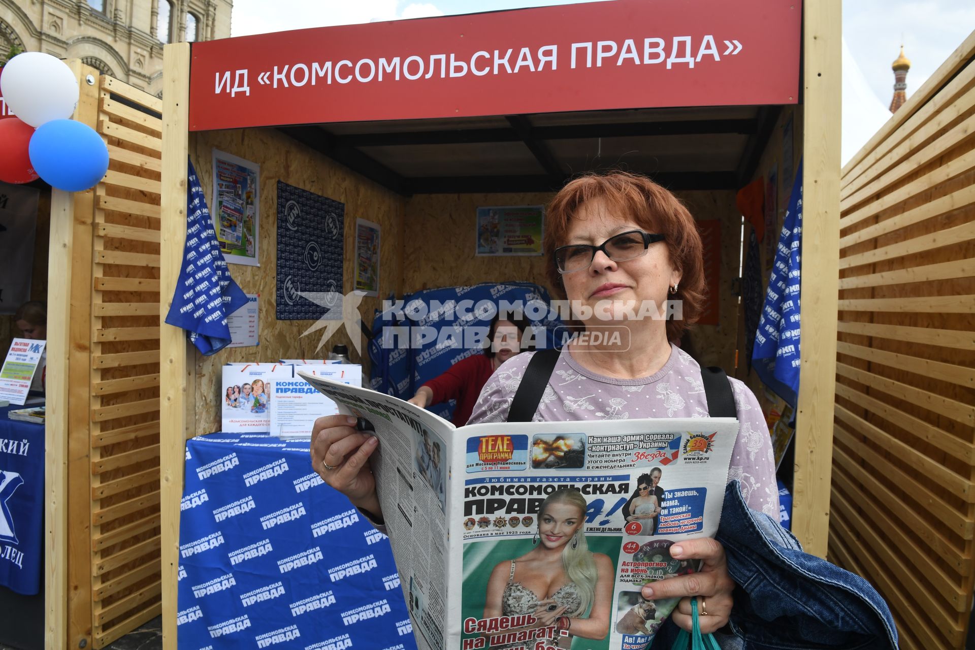 Москва. Женщина читает газету у стенда Издательского дома `Комсомольская правда` на IX ежегодном книжном фестивале `Красная площадь`.