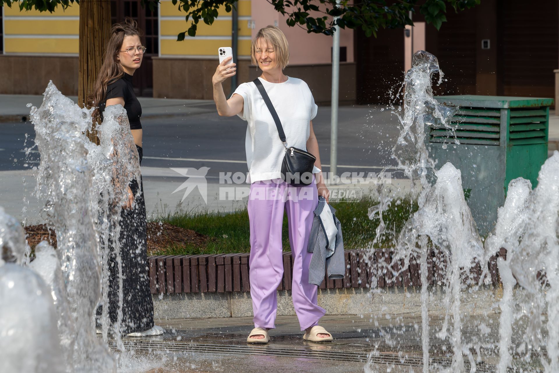 Москва. Женщина фотографируется  у фонтана.