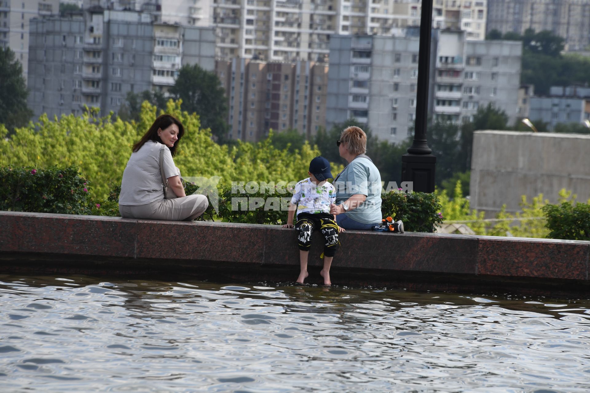 Москва.  Женщины с ребенком сидяту фонтана на Поклонной горе.