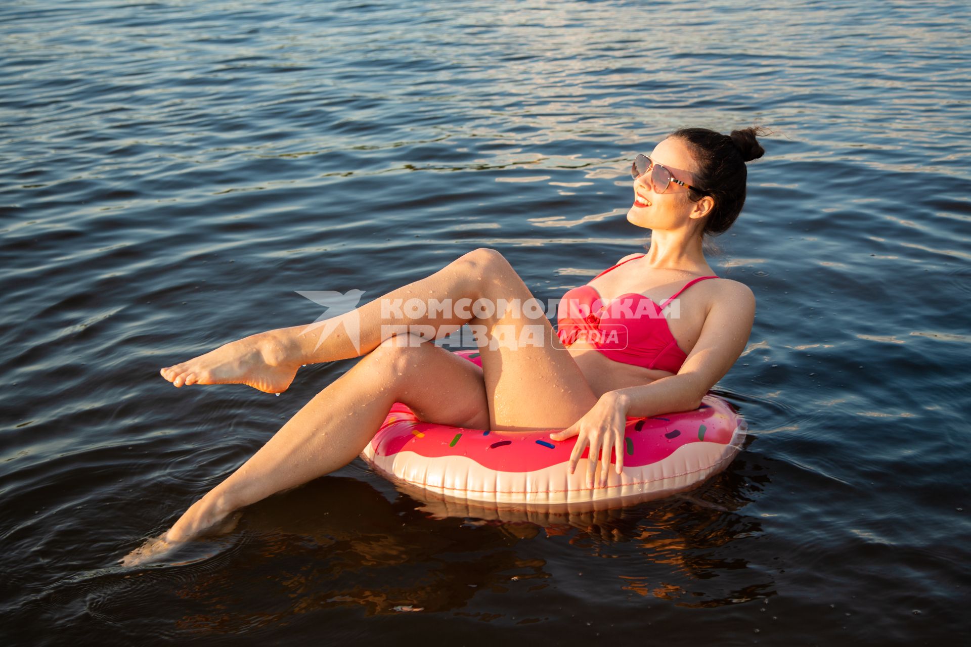 Москва. Девушка плавает на надувном круге в виде пончика на пляже Серебряный бор № 2.