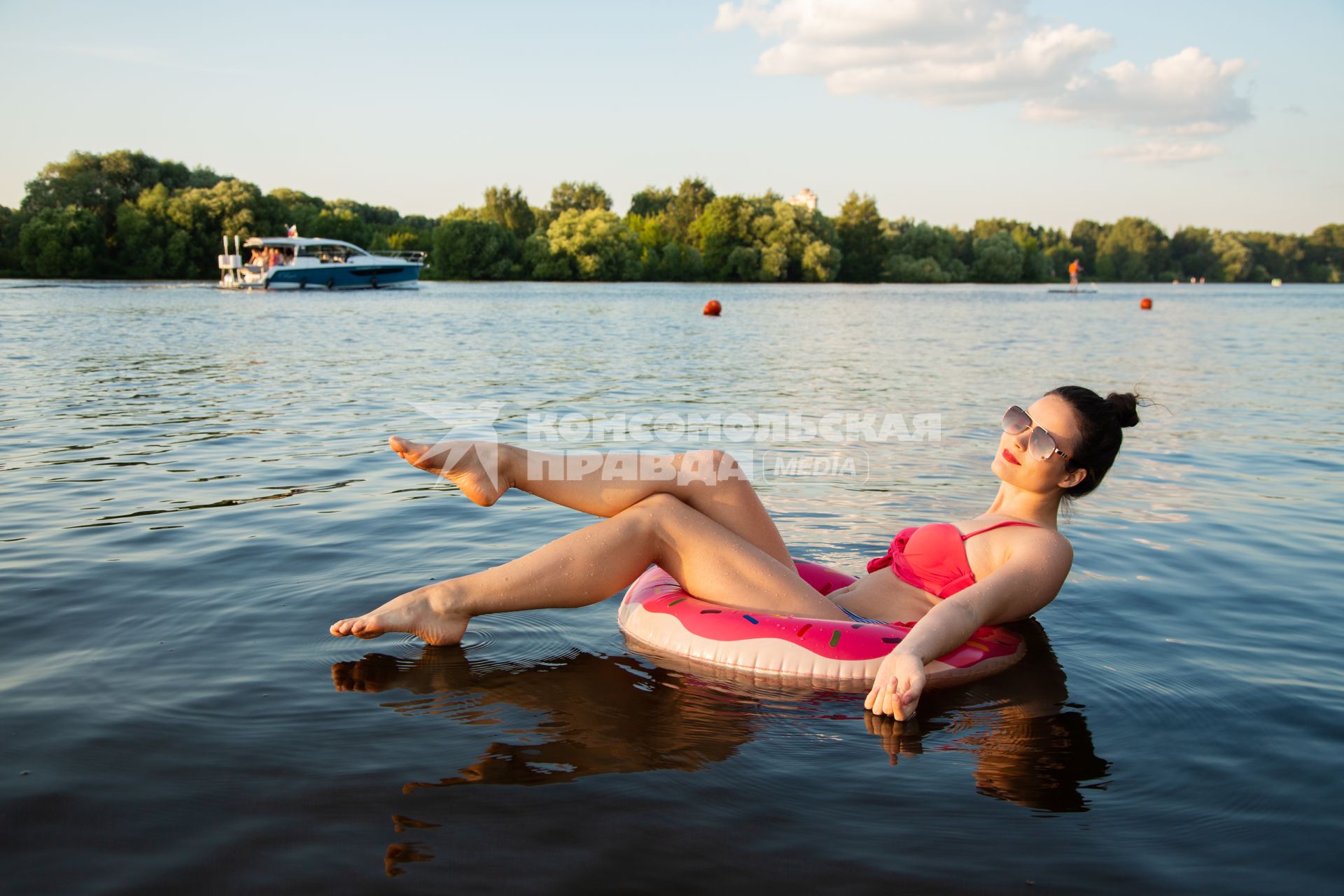Москва. Девушка плавает на надувном круге в виде пончика на пляже Серебряный бор № 2.