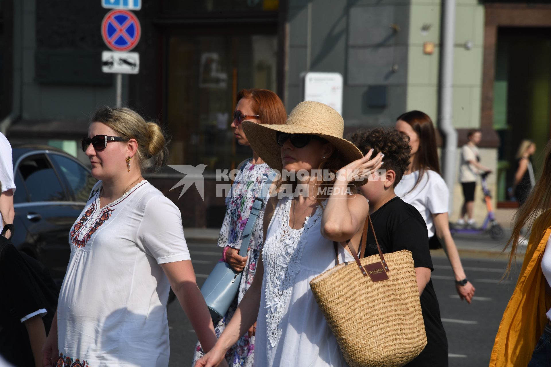 Москва. Женщина в шляпе и в солнцезащитных очках идет по улице.