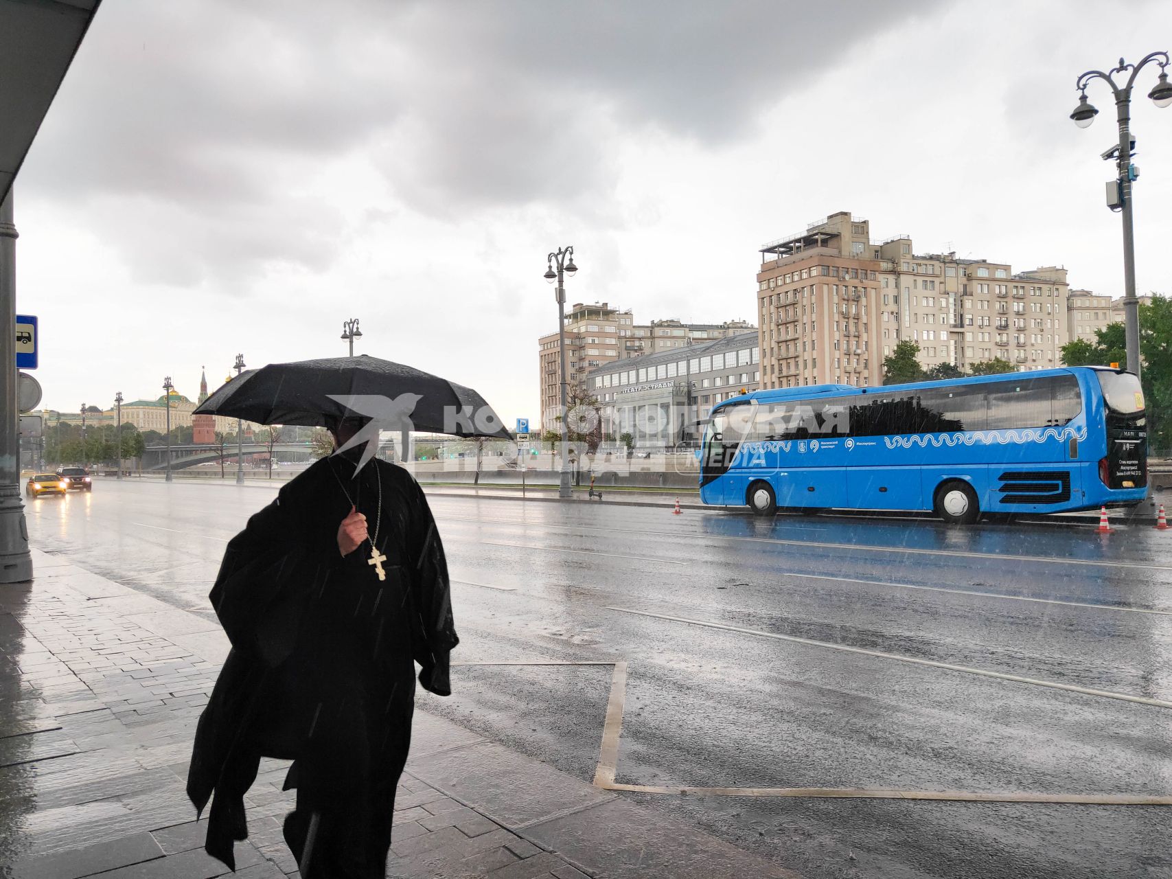 Москва. Священнослужитель с зонтом во время дождя на Пречистенской набережной.