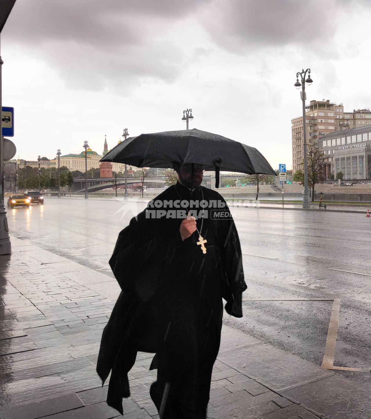 Москва. Священнослужитель с зонтом во время дождя на Пречистенской набережной.