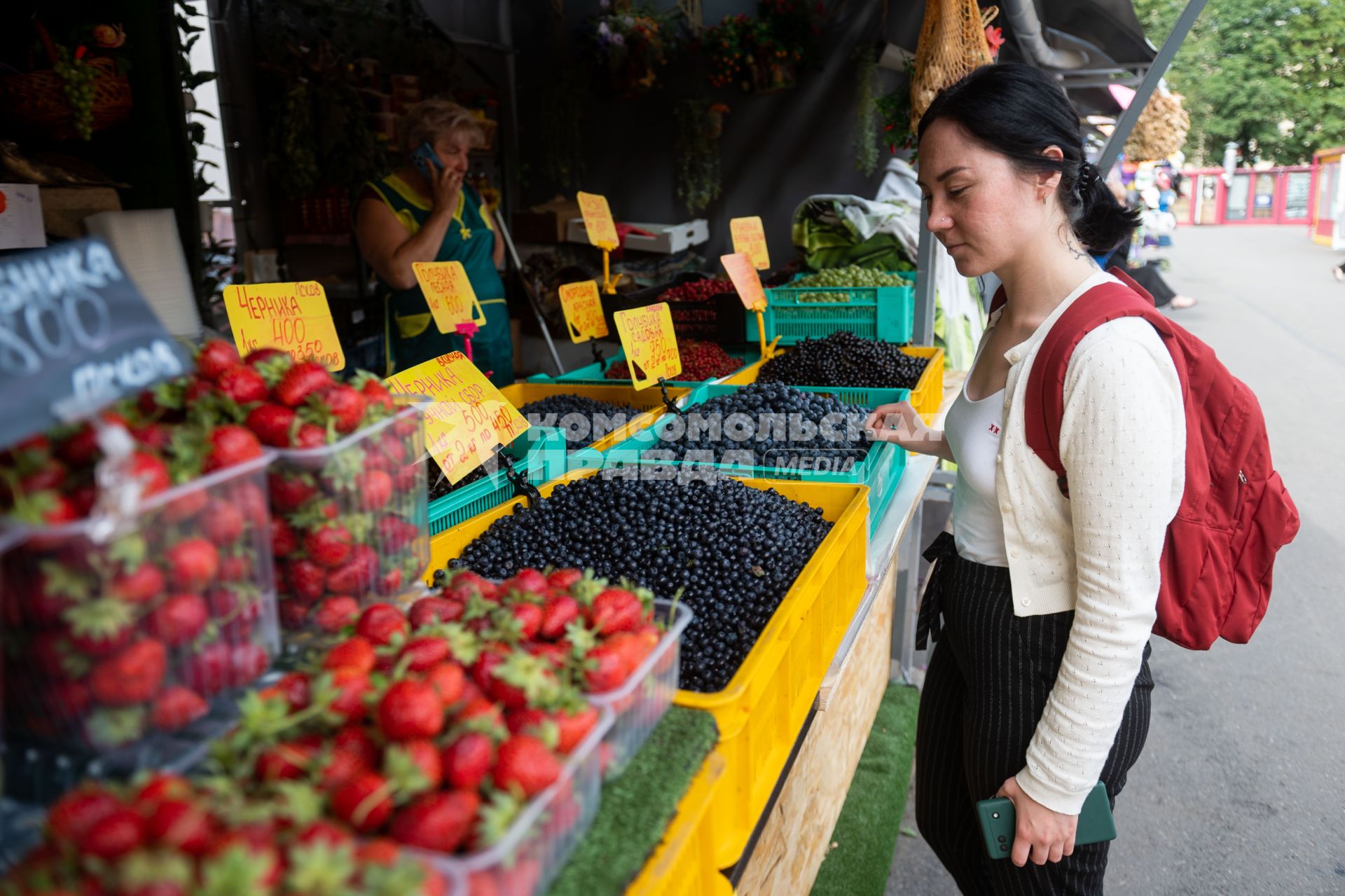 Санкт-Петербург. Девушка выбирает ягоды на Сенном рынке.