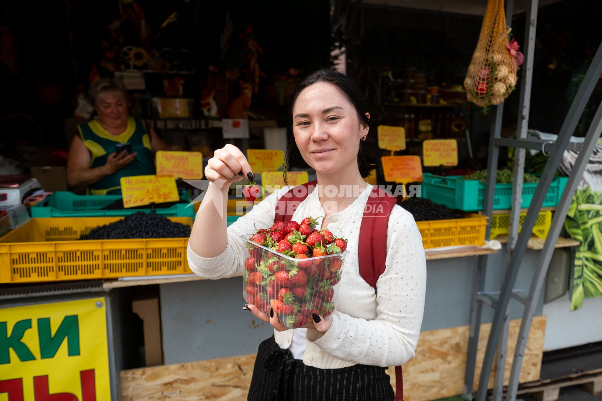 Санкт-Петербург. Девушка держит в руках лоток с клубникой на Сенном рынке.