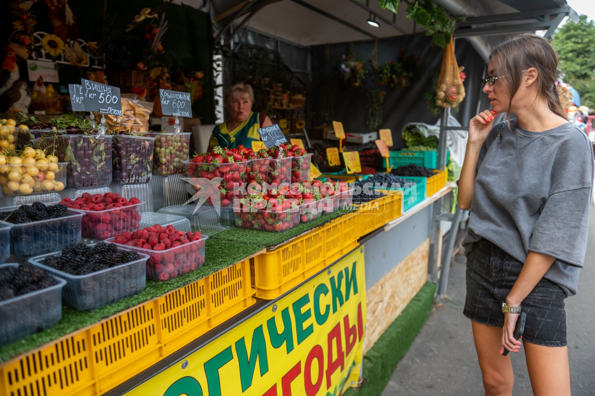 Санкт-Петербург. Девушка выбирает ягоды на Сенном рынке.