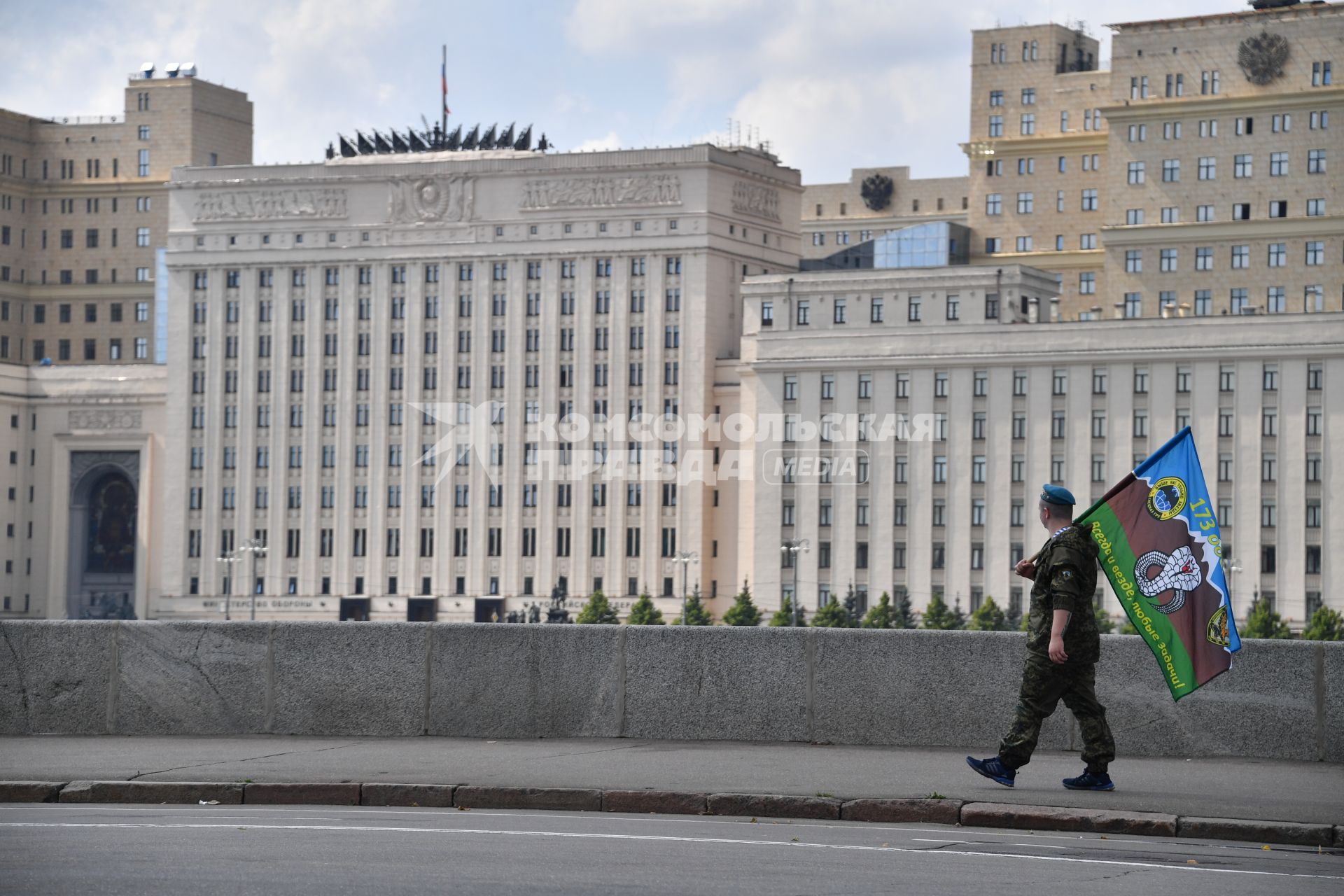 Москва. Десантник с флагом идет по Пушкинской набережной и смотрит на министерство обороны РФ в День Воздушно-десантных войск России.