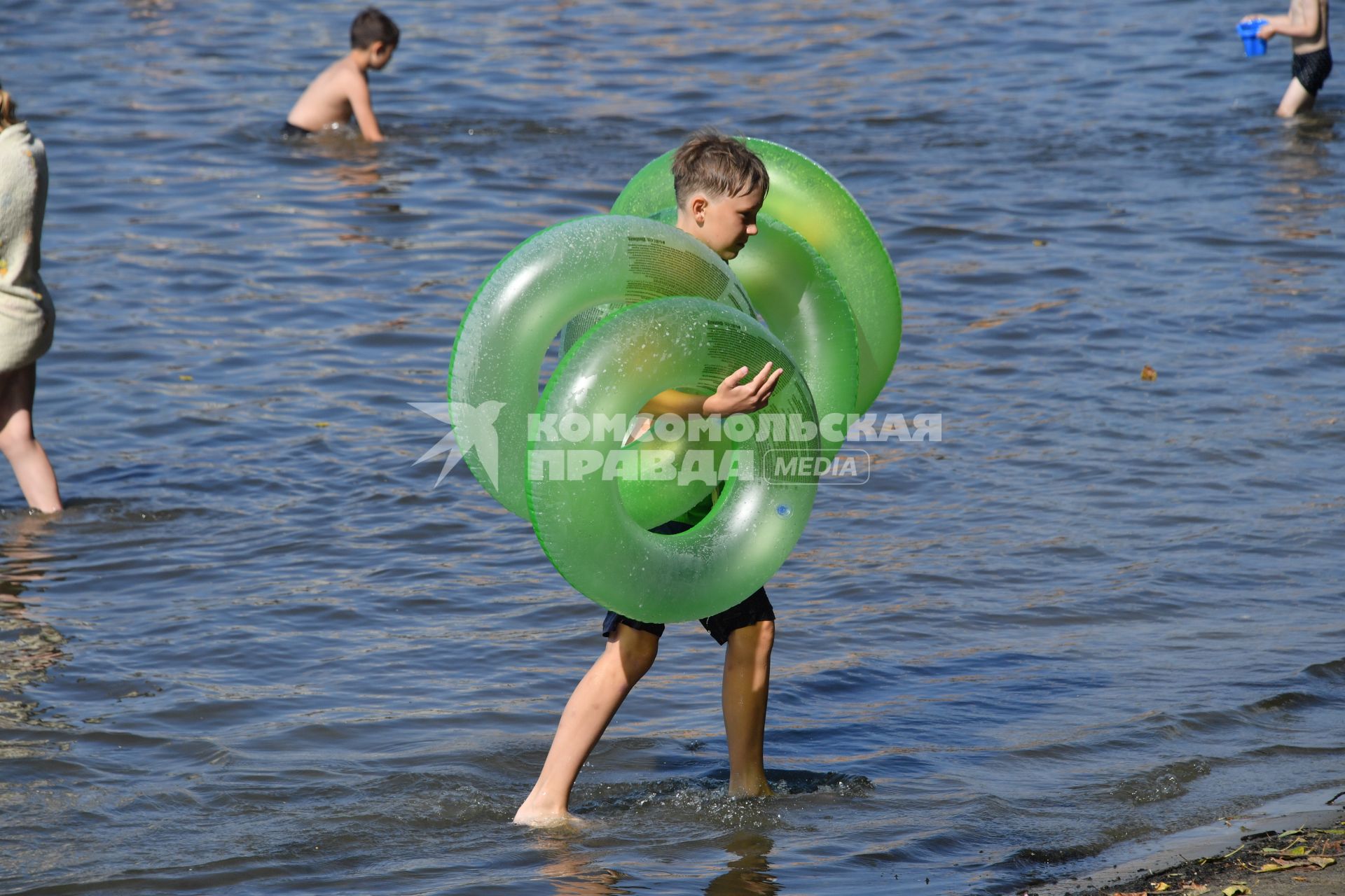 Москва. Мальчик несет надувные круги на пляже озера Белое в районе Косино-Ухтомское.