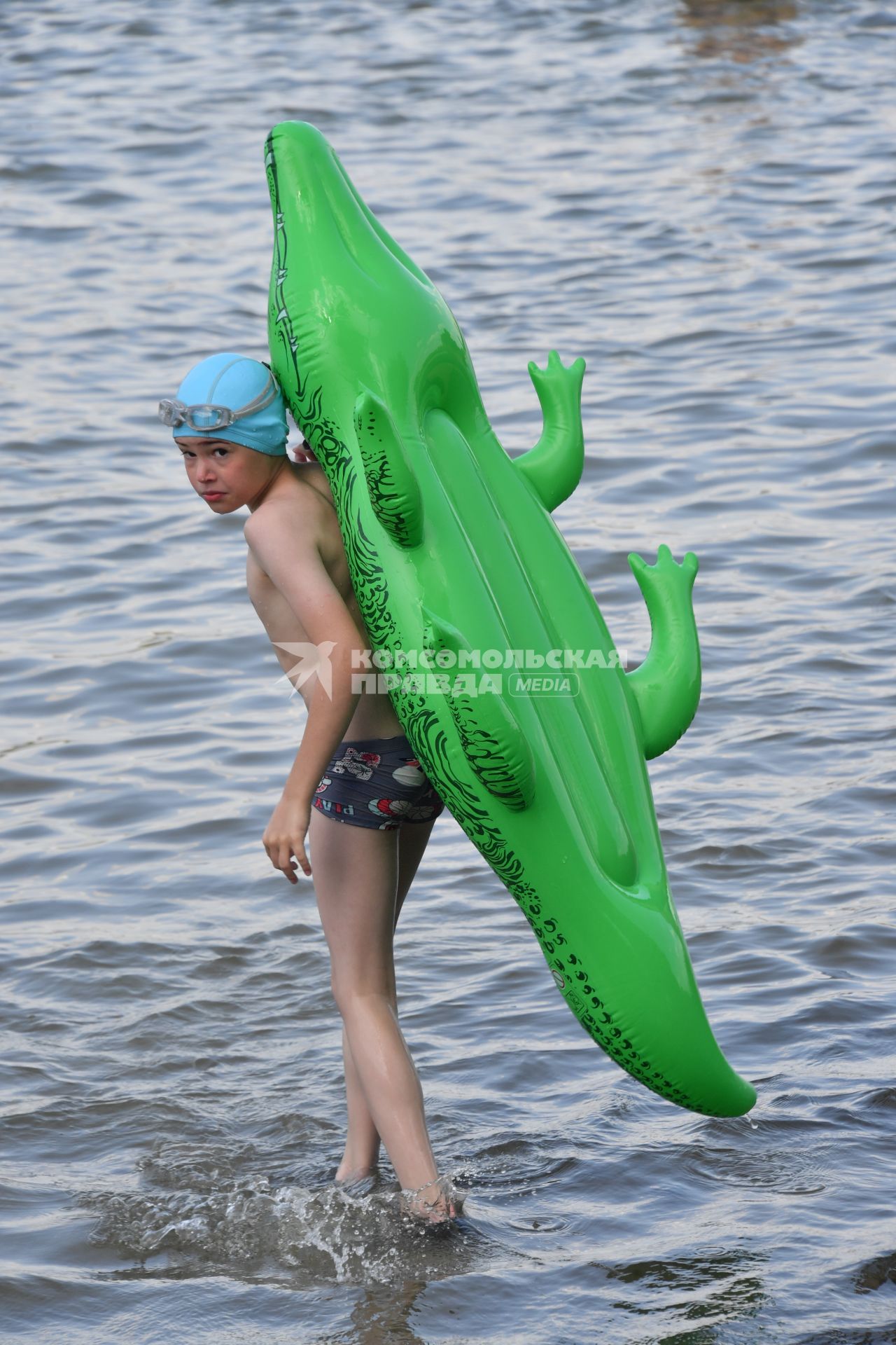 Москва. Мальчик с надувным крокодилом купается в озере Белое в районе Косино-Ухтомское.