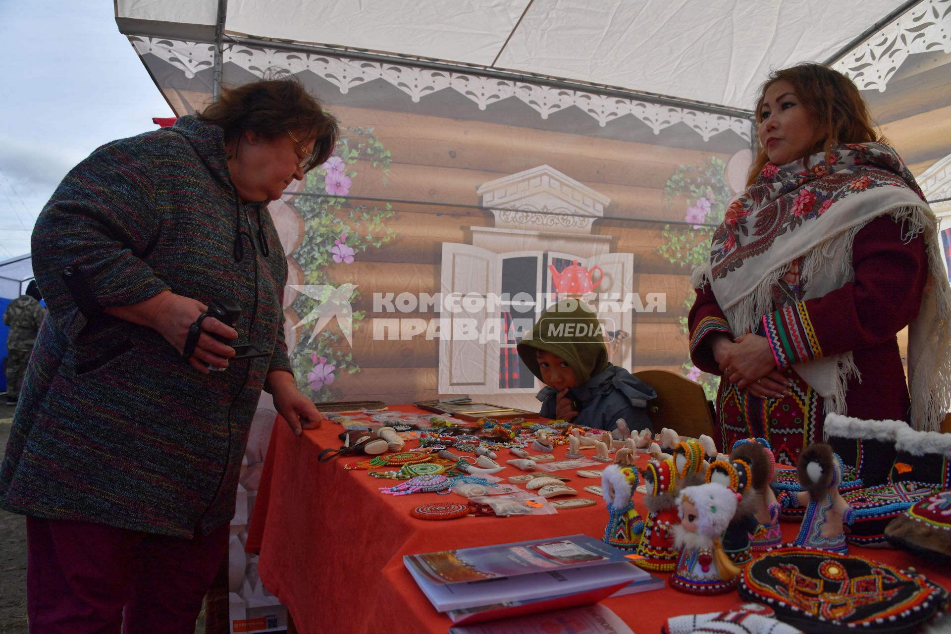 Красноярский край. Хатанга.  Женщина покупает национальные сувениры на празднике День оленевода.