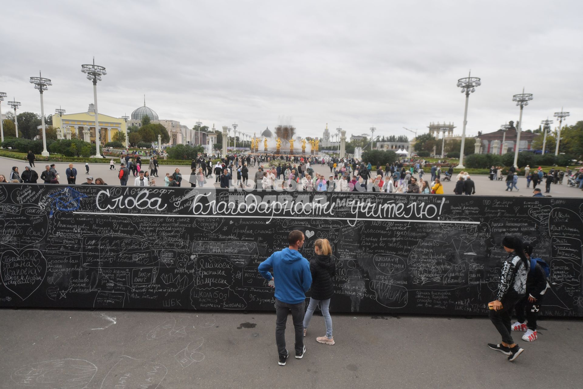 Москва.   Празднование Дня города Москвы на ВДНХ.  Молодые люди у  доски `Слов благодарности учителю`.