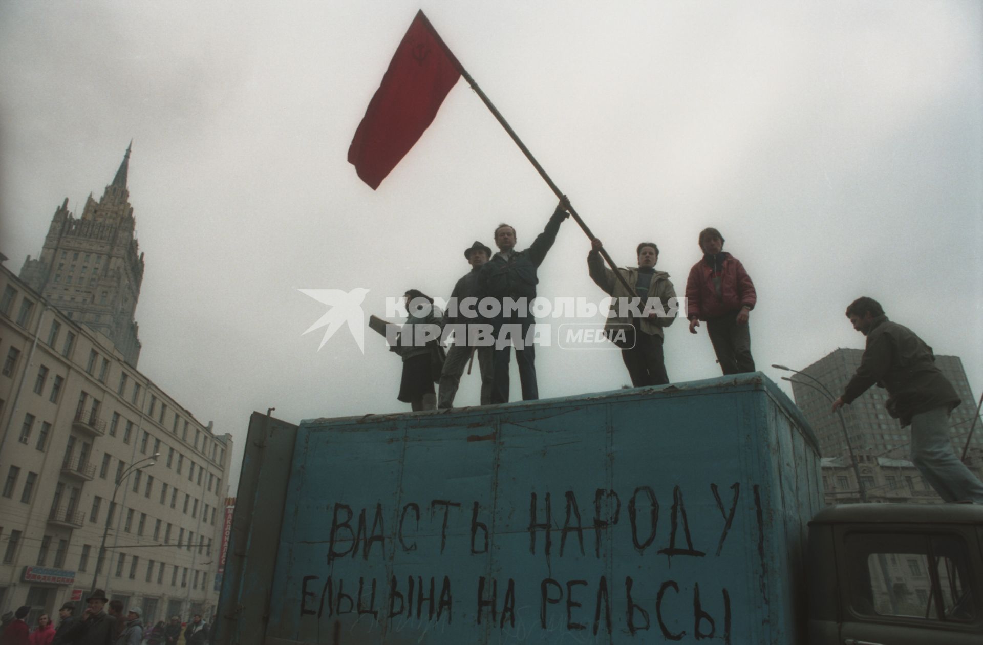 Москва. 1993г. Октябрьский путч. Люди с красным флагом на крыше автомобильного фургона с надписью `Власть народу! Ельцина на рельсы`.