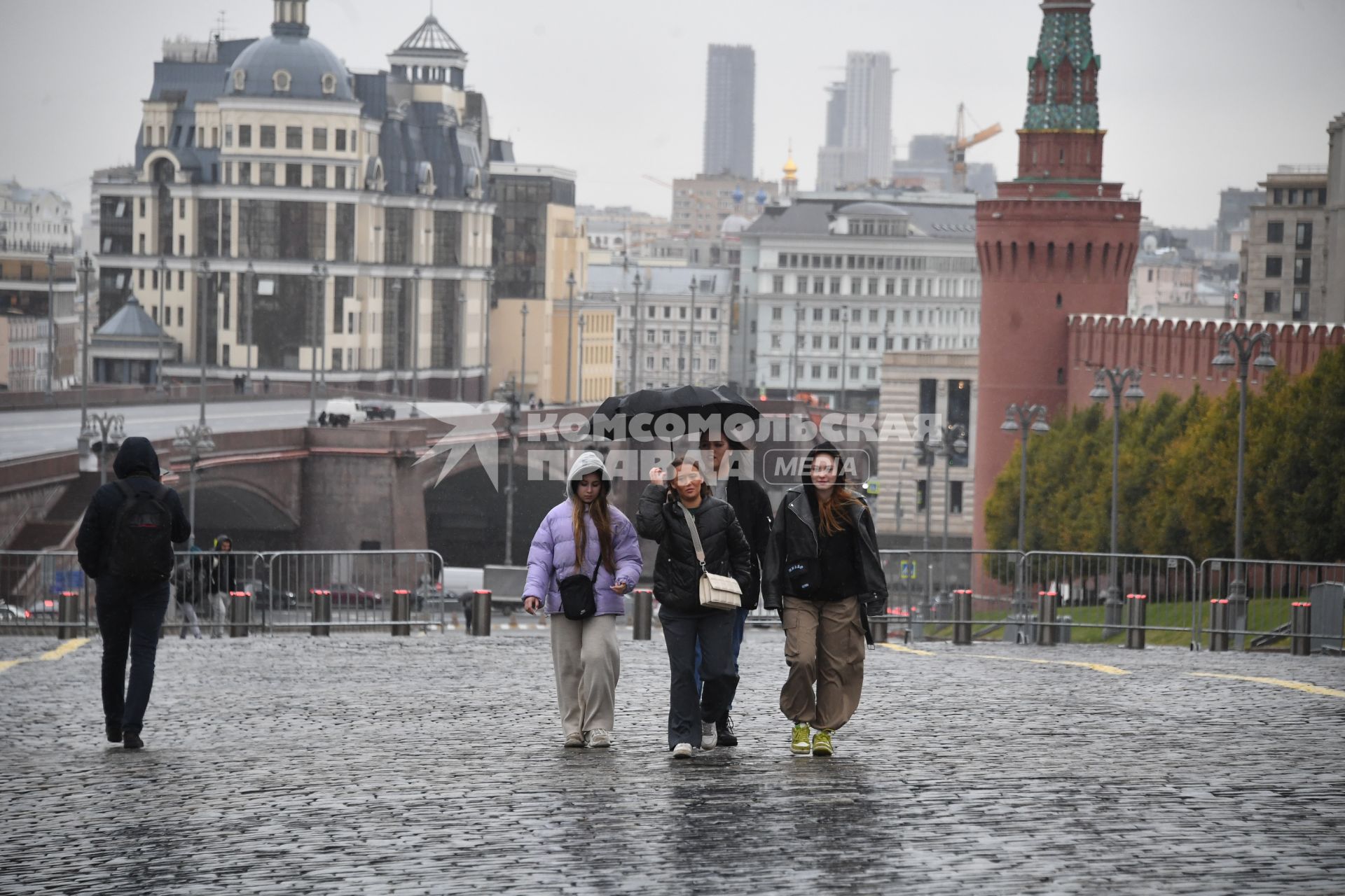 Москва. Девушки гуляют под зонтом  на Красной площади во время дождя.