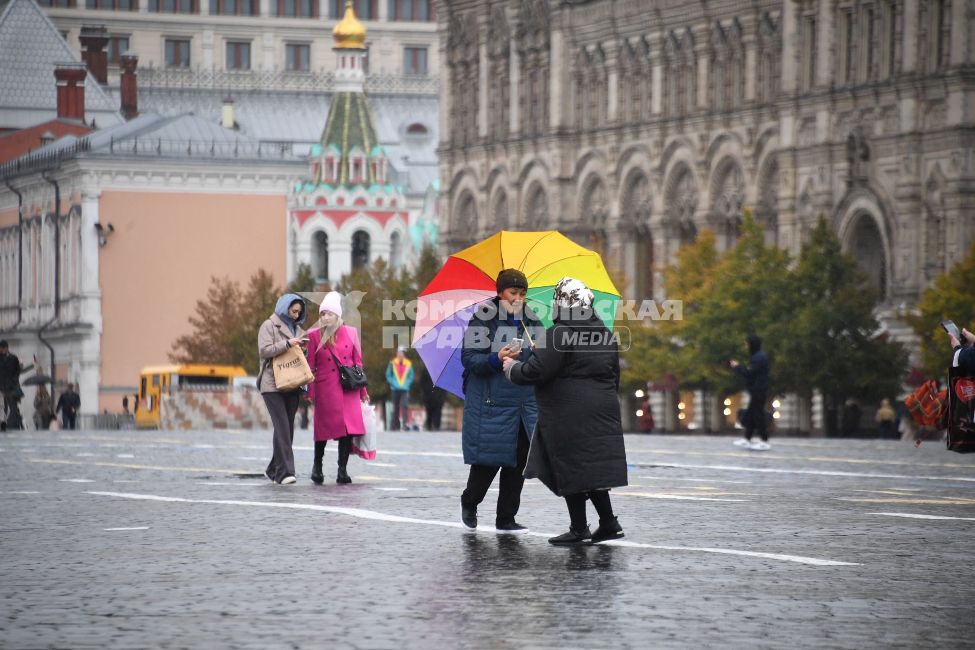 Москва.  Женщины  под зонтом на Красной площади во время дождя.