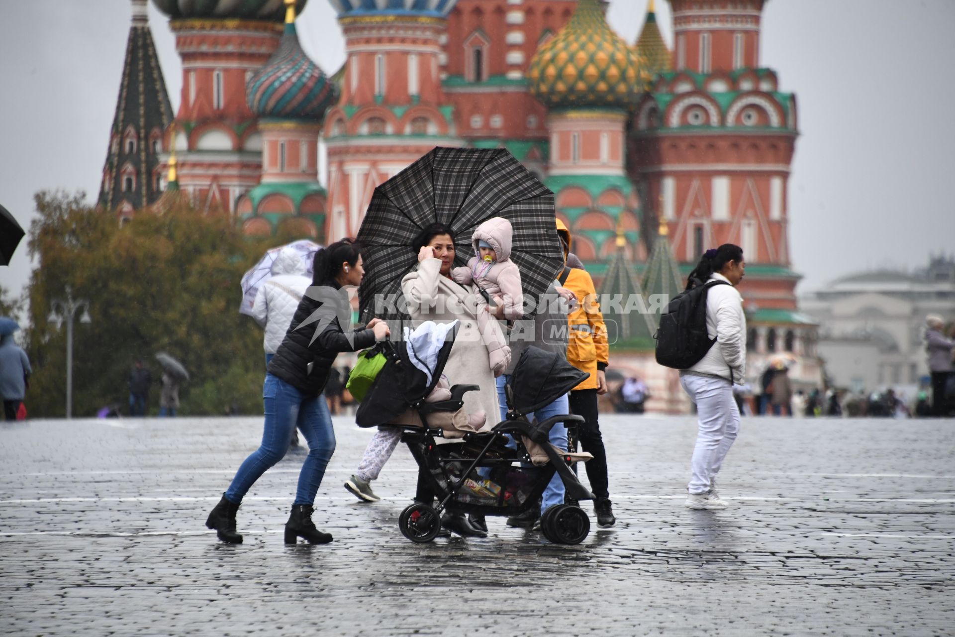 Москва.  Женщина с детьми на Красной площади во время дождя.