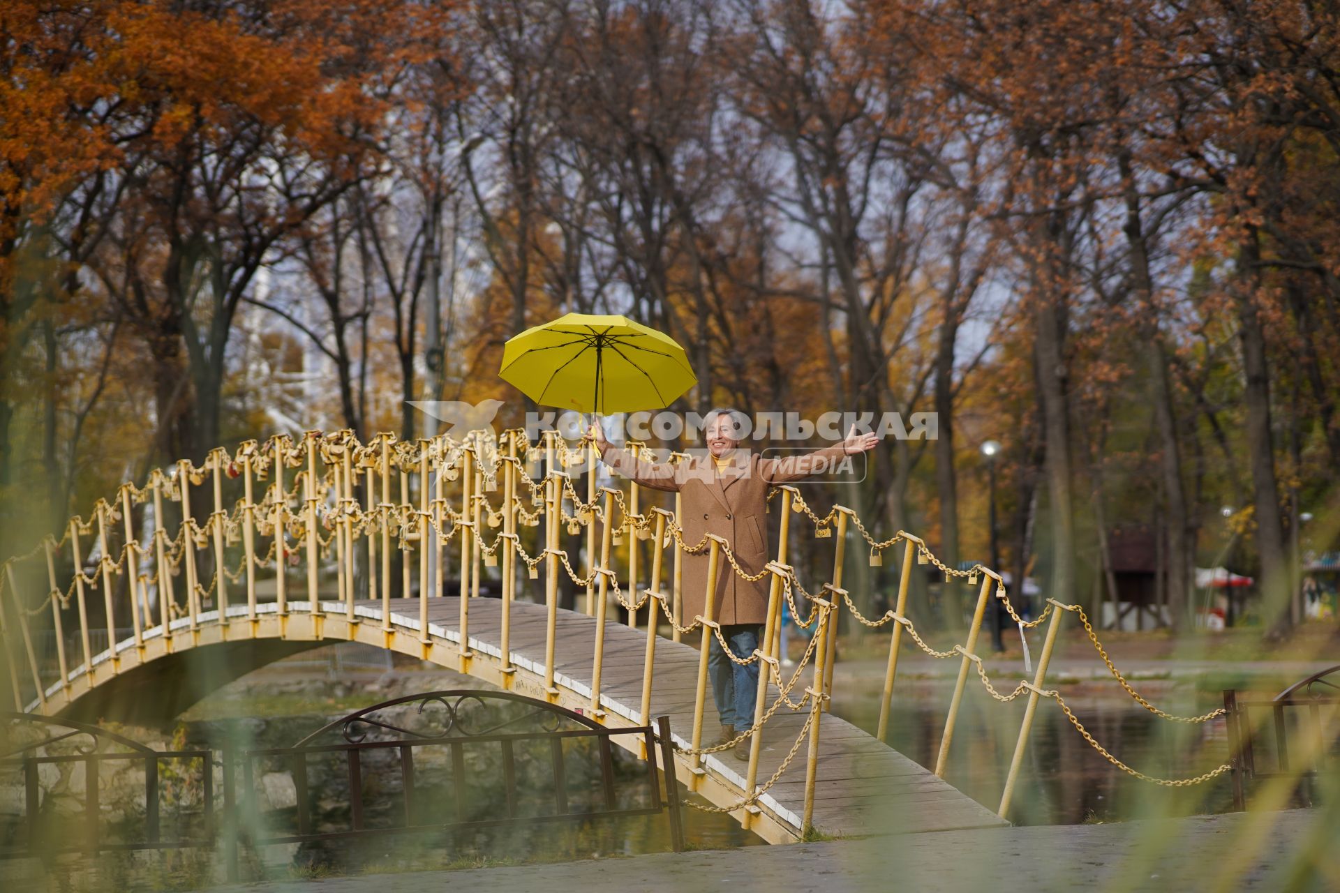 Самара. Женщина стоит на мосту с зонтом желтого цвета.