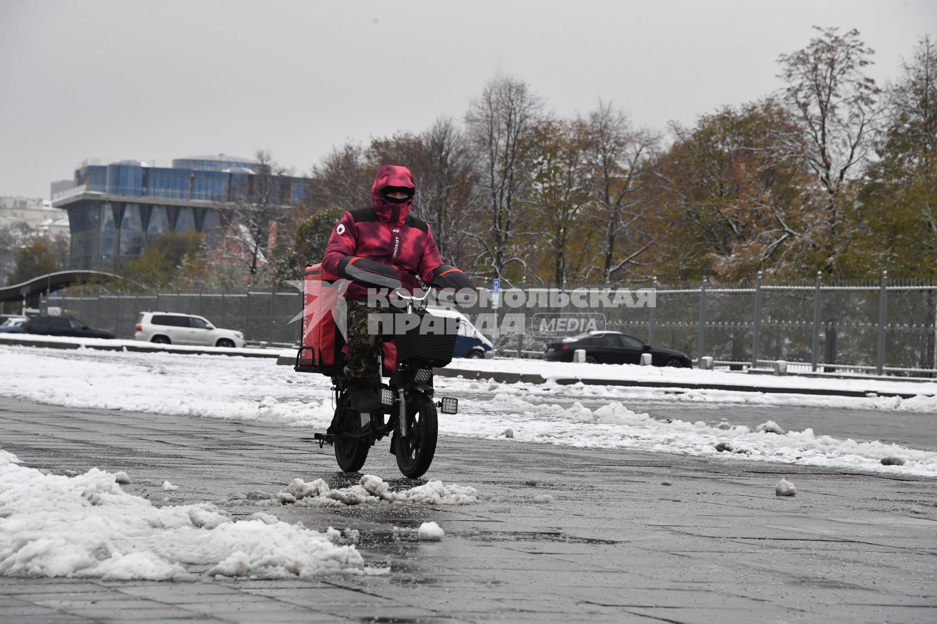 Москва. Сотрудник службы доставки на улице города во  время  снегопада.