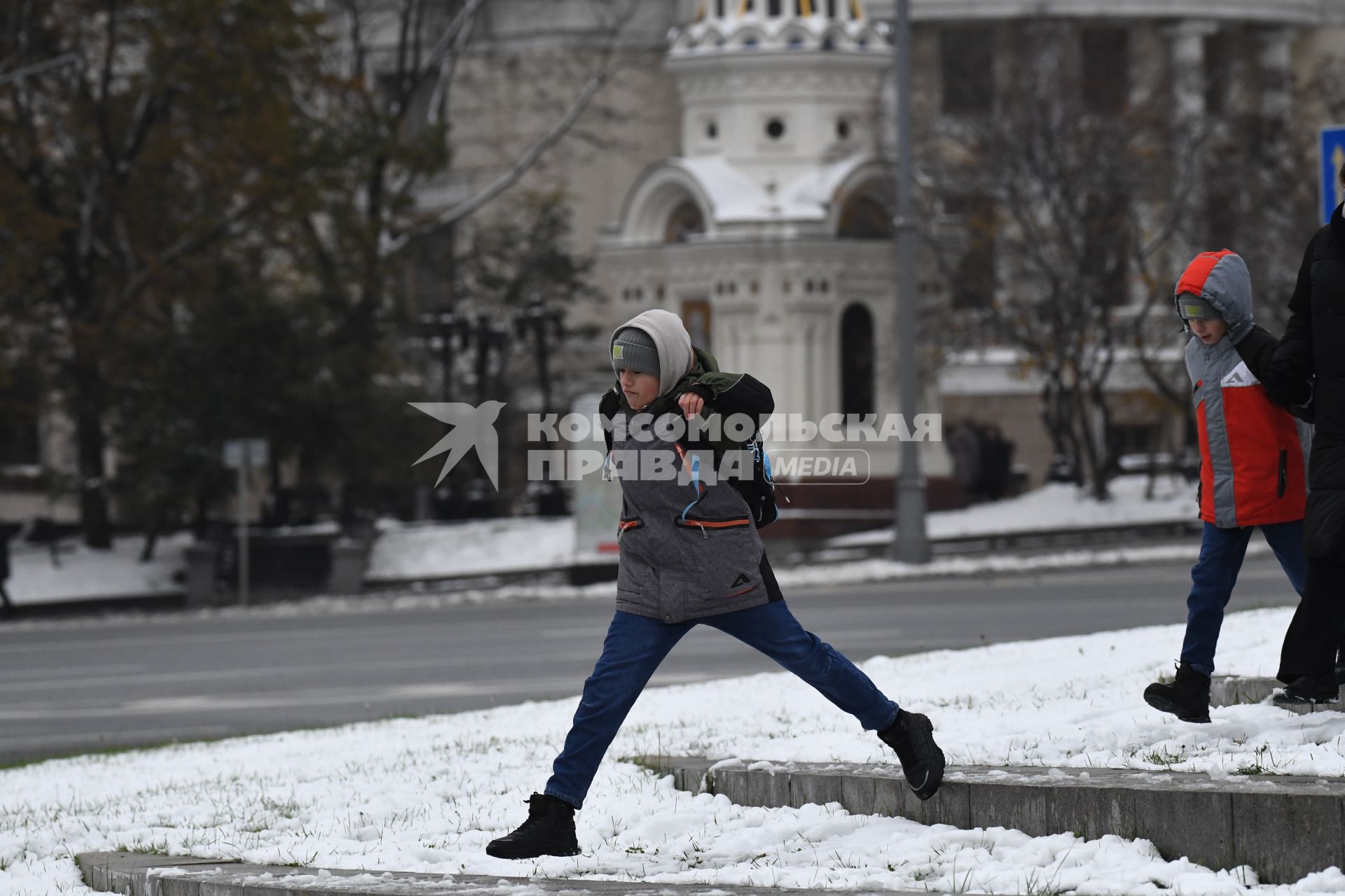 Москва. Мальчик перепрыгивает черех  лужу.