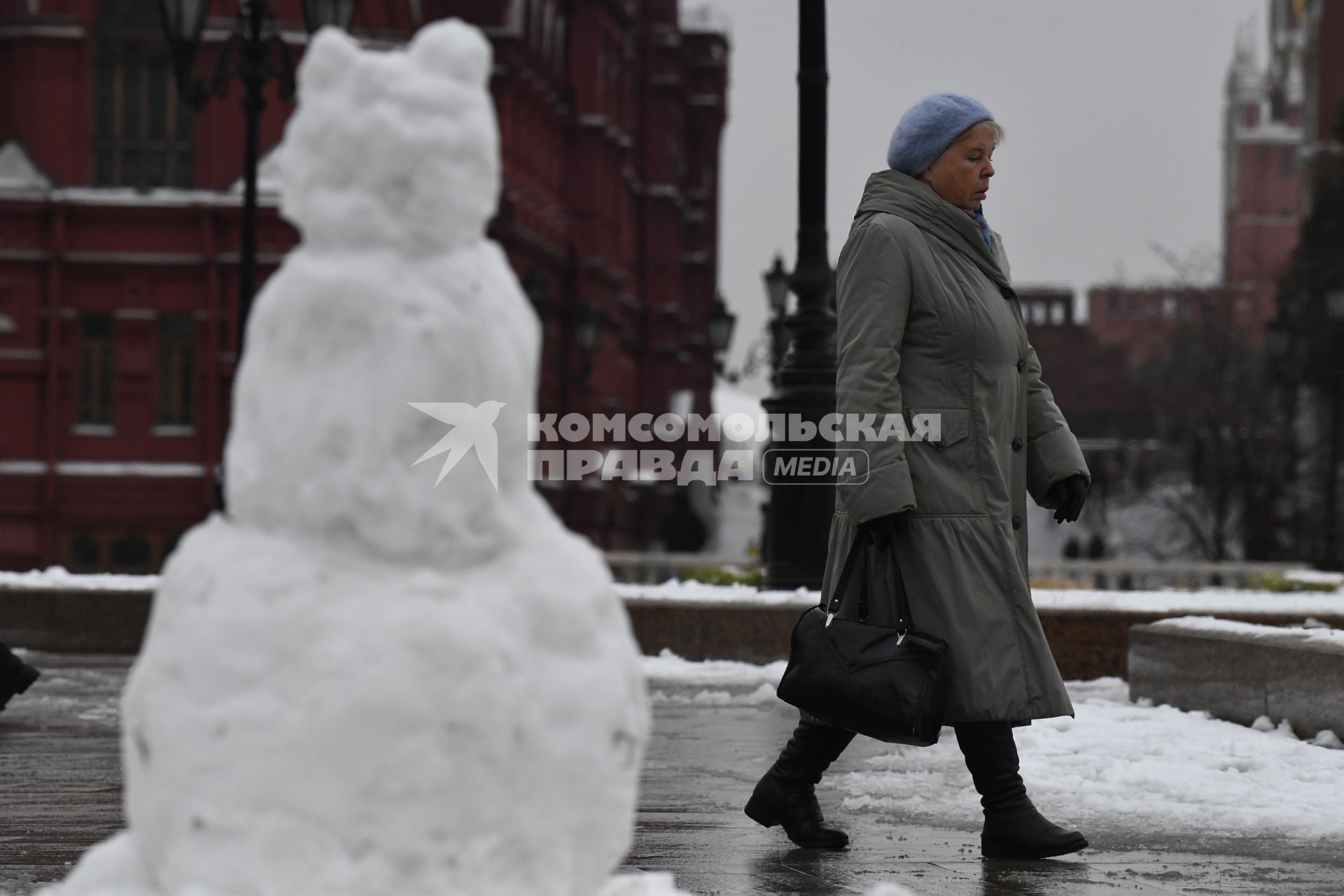 Москва.   Женщина и снеговик на улице города.