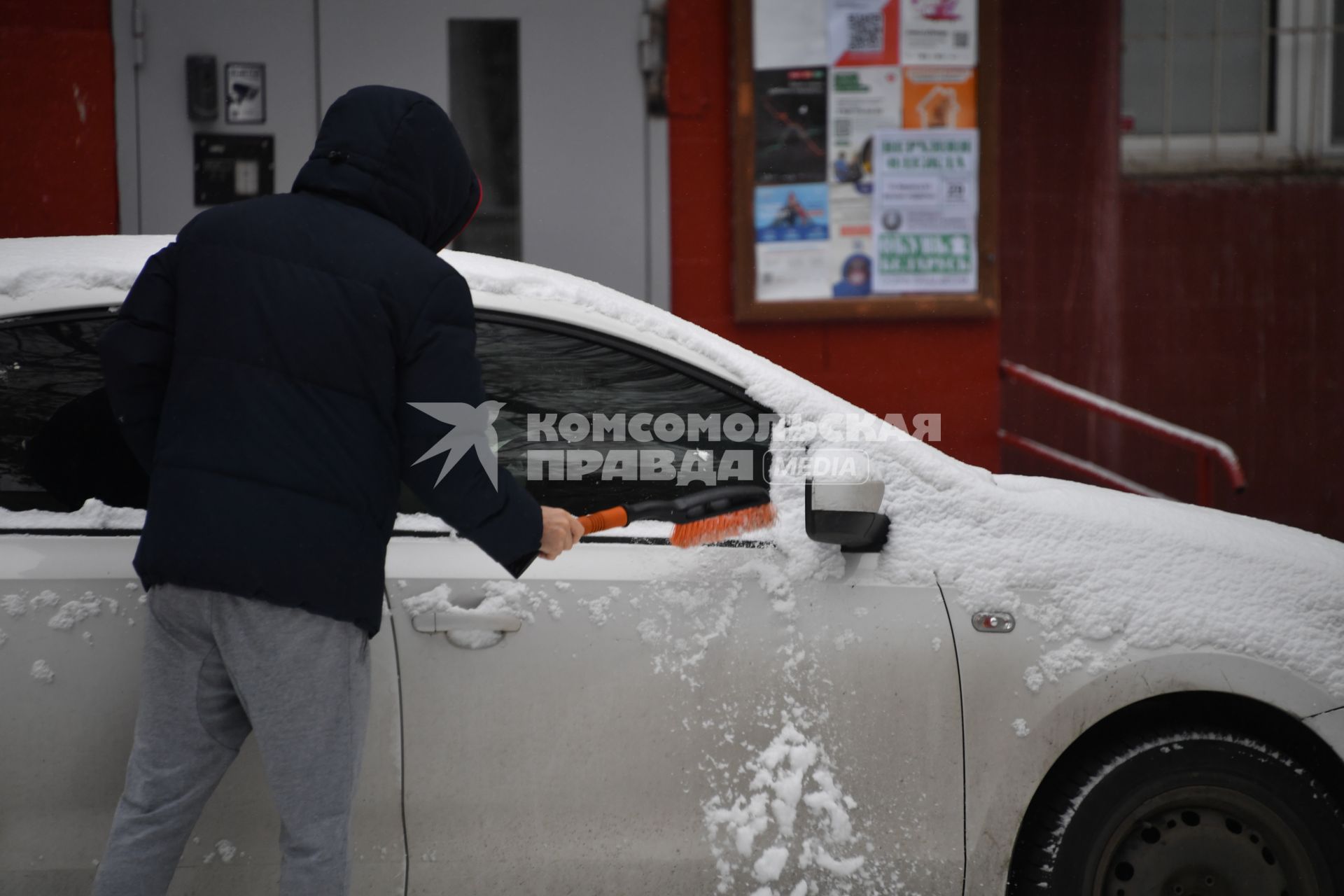 Москва. Автовладелец счищает снег с машины.