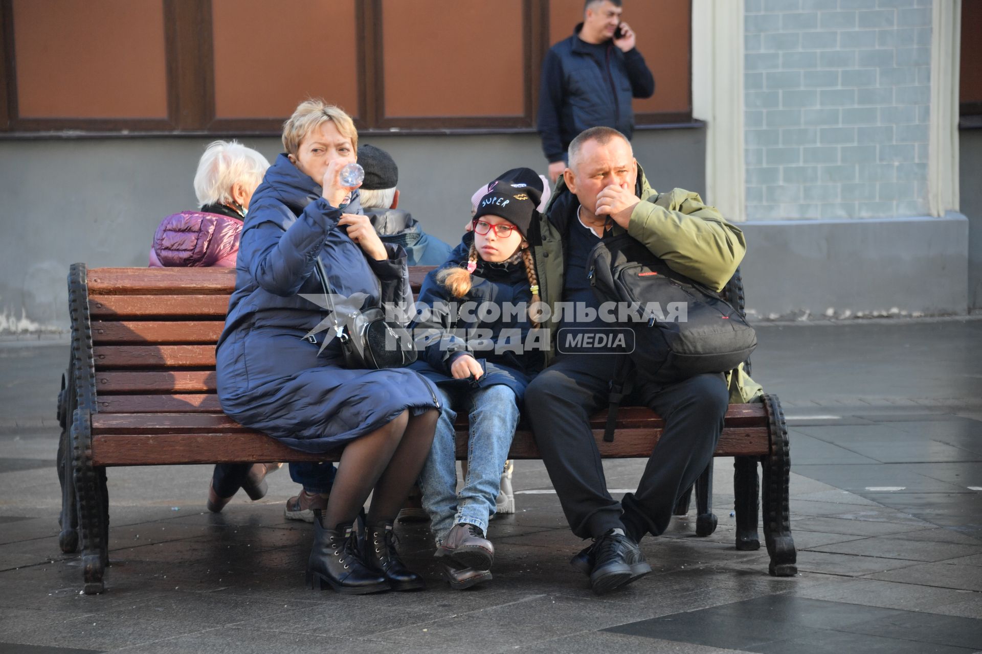 Москва. Семья отдыхает на скамейке на улице.