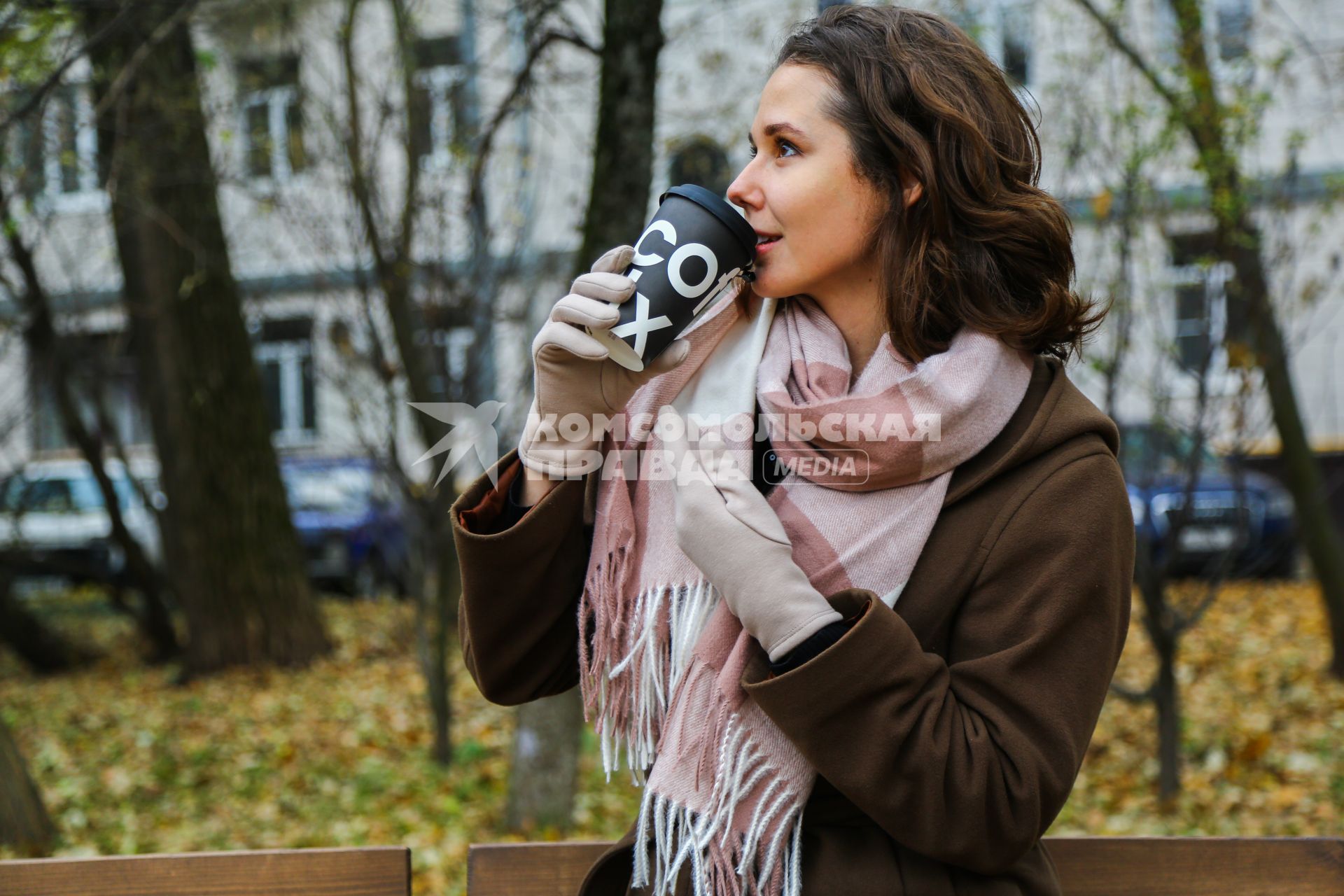 Москва.  Девушка пьет кофе на улице.