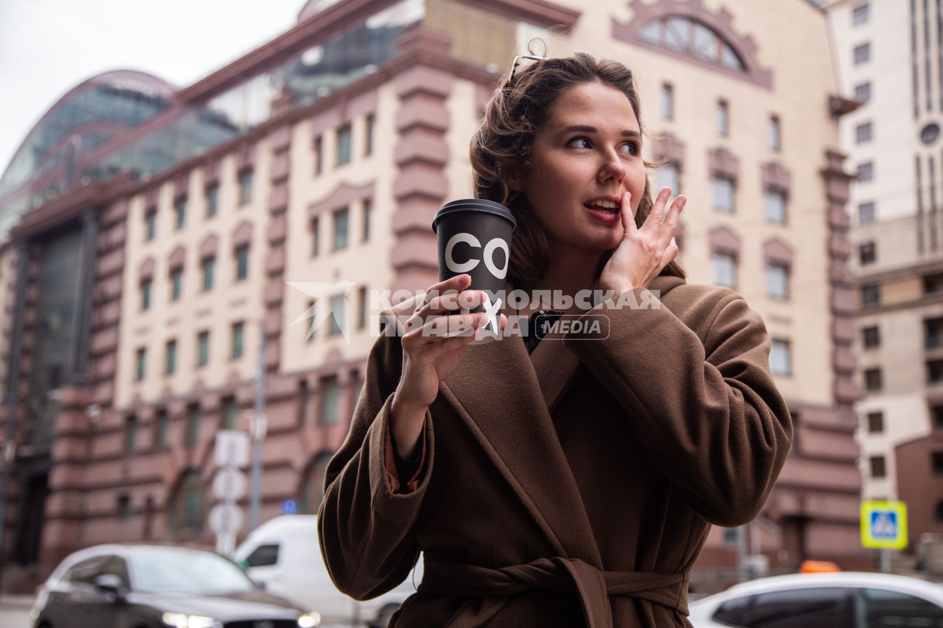 Москва.  Девушка пьет кофе на улице.