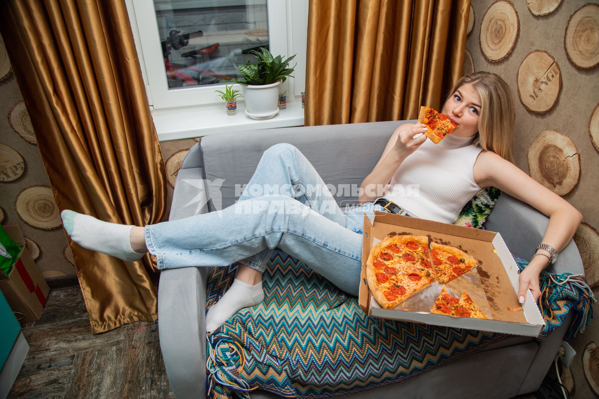 Москва.  Девушка дома  ест пиццу.