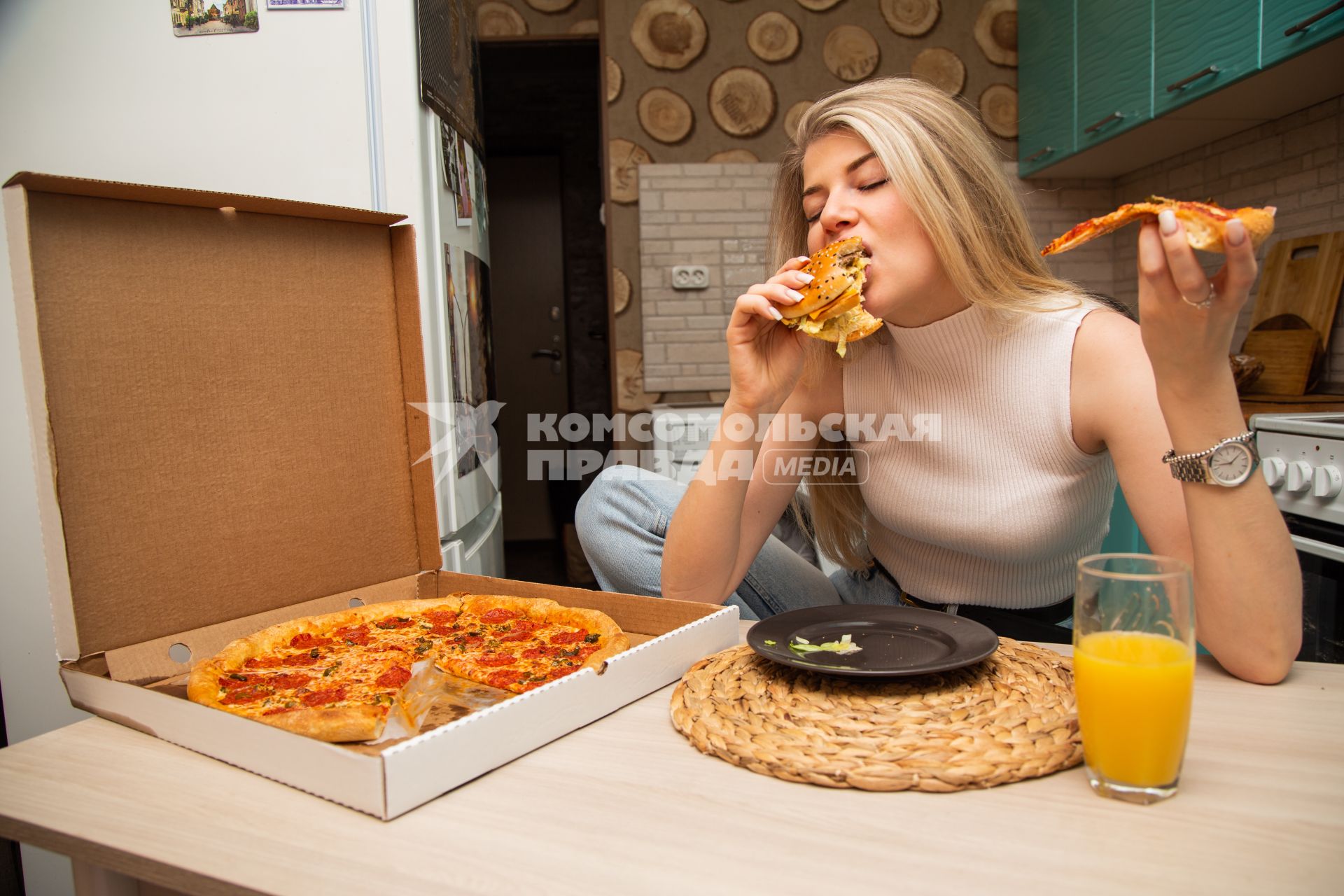 Москва.  Девушка ест пиццу дома.