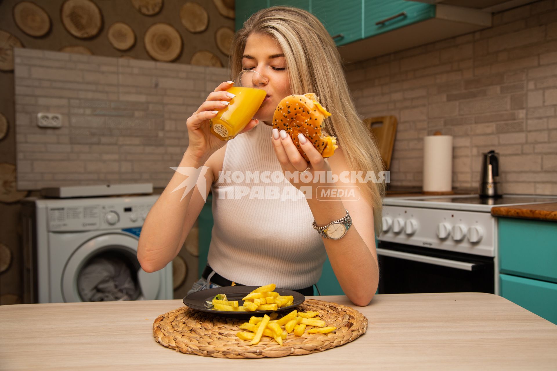 Москва. Девушка ест гамбургер дома.