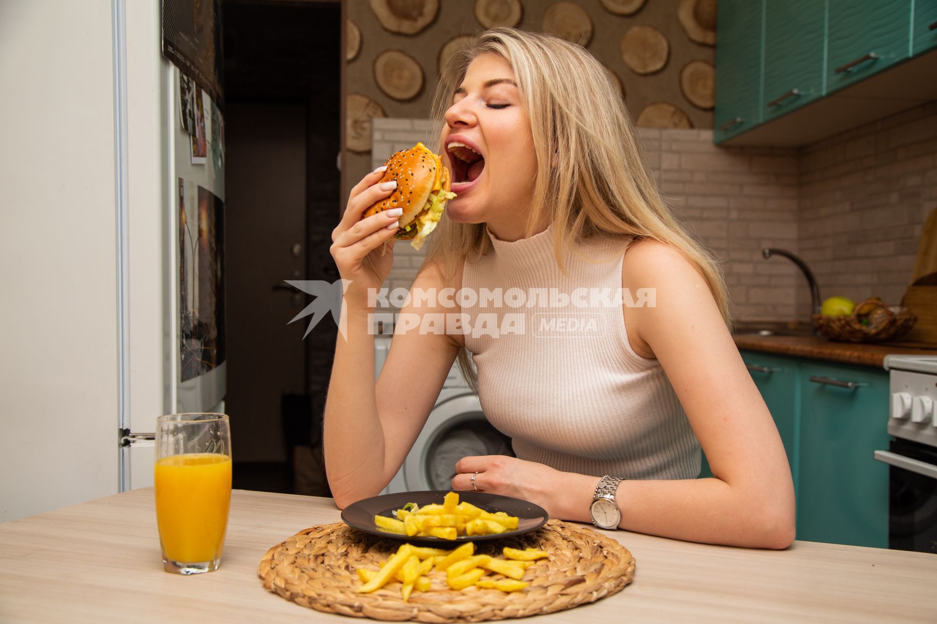 Москва. Девушка ест гамбургер дома.
