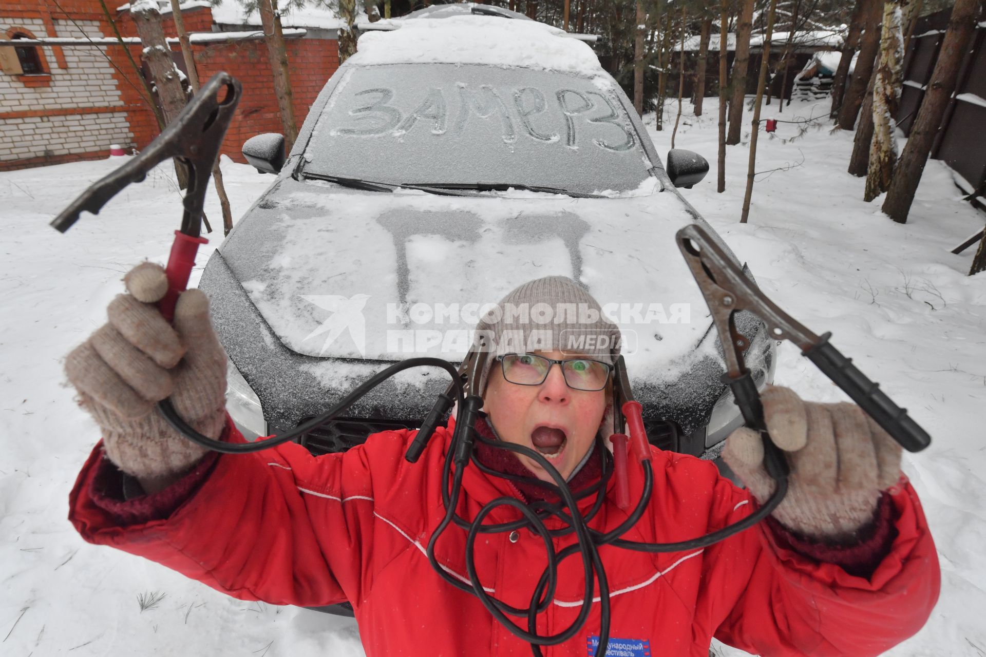 Женщина заводит автомобиль в мороз
