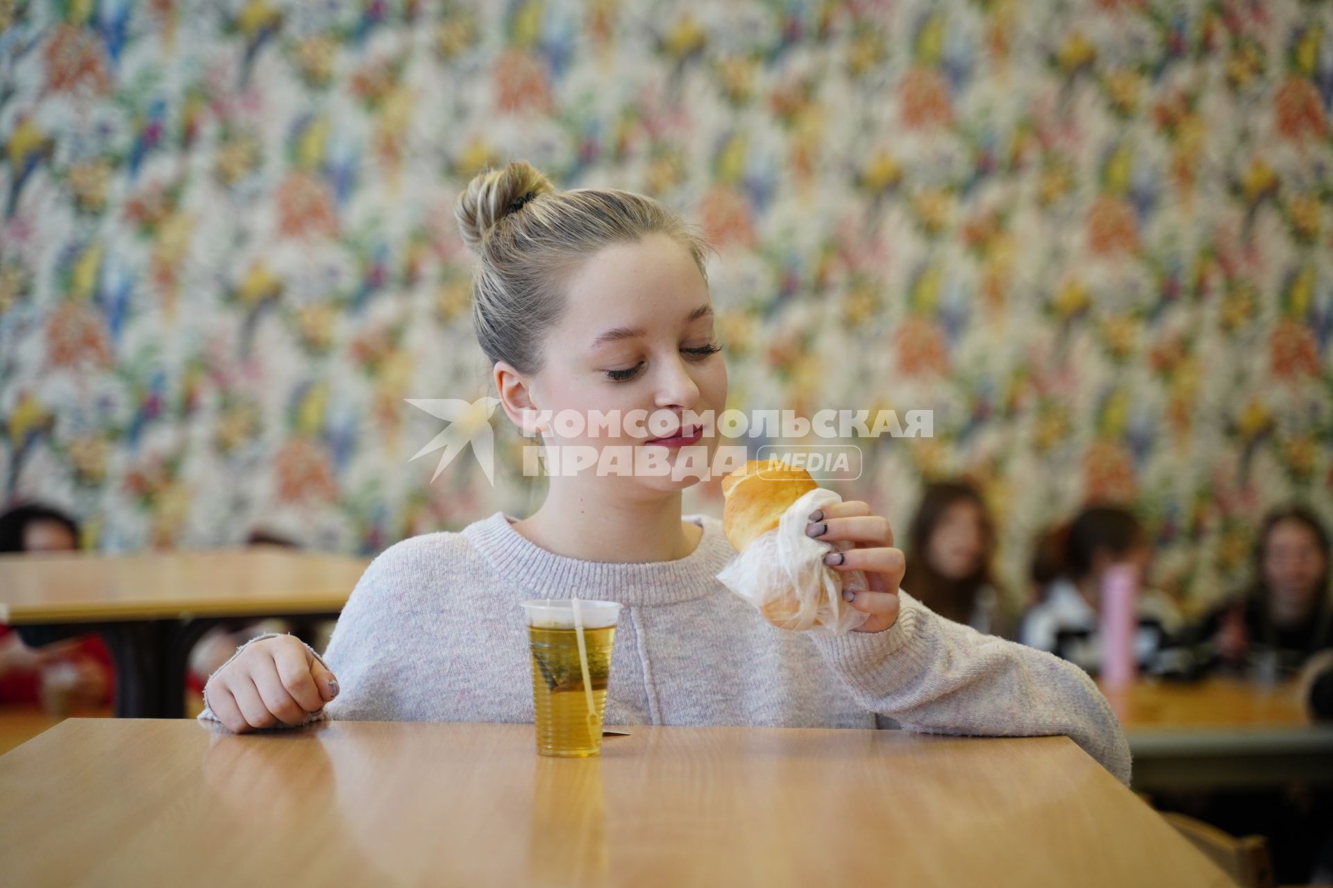 Девушка пьет чай с булочкой