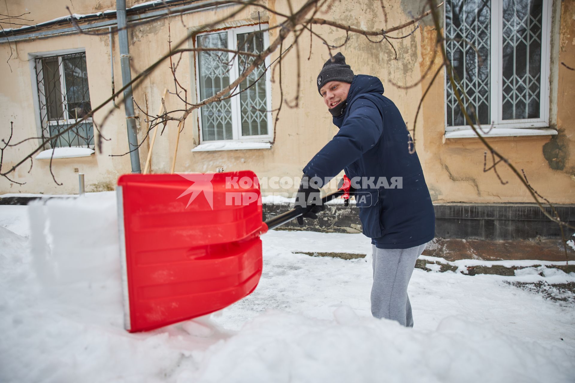 Мужчина чистит двор от снега